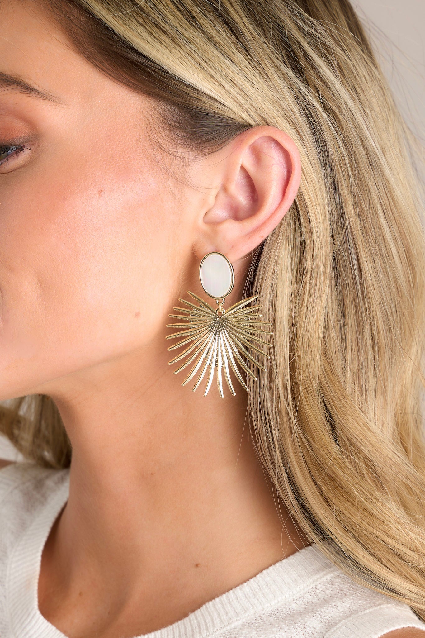 These gold earrings feature a faux opalescent stud, a gold statement drop, and secure post backings.