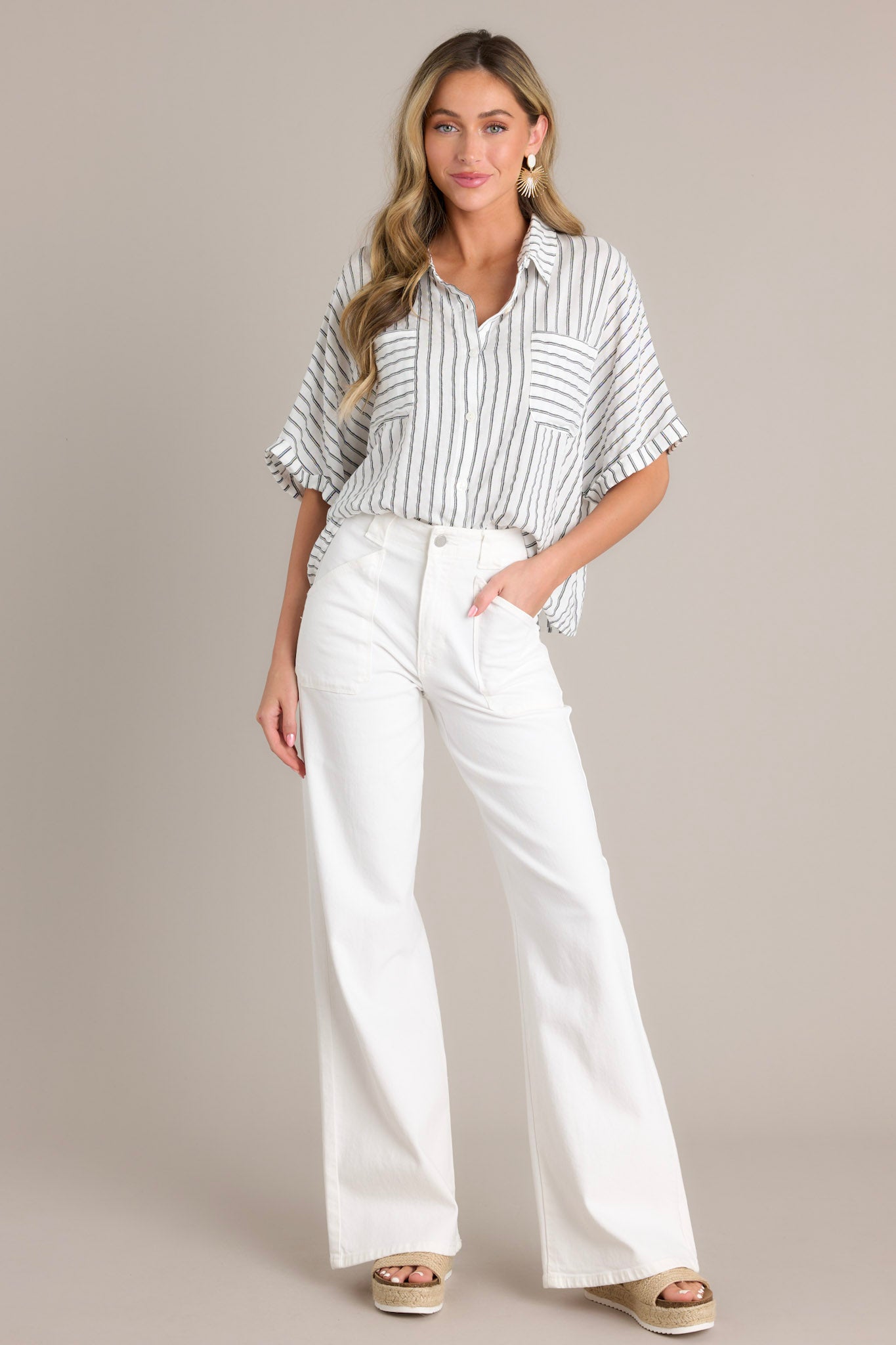 Full length view of a black stripe top with a collared neckline, a functional button front, functional breast pockets, vertical & horizontal stripes, and short cuffed dolman sleeves