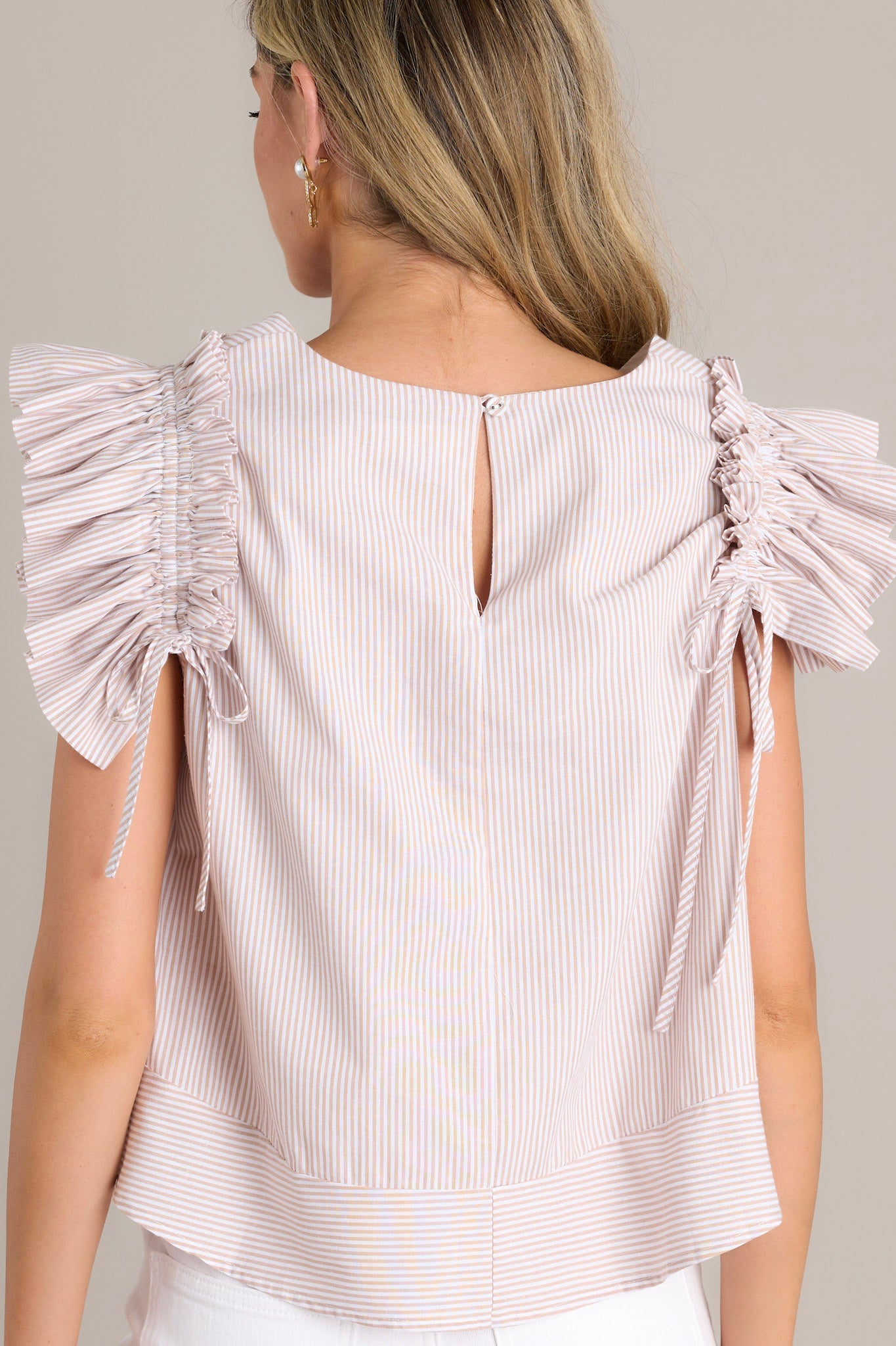 Back view of a taupe stripe top highlighting the vertical stripes, relaxed loose fit, and the layered ruffle sleeves.