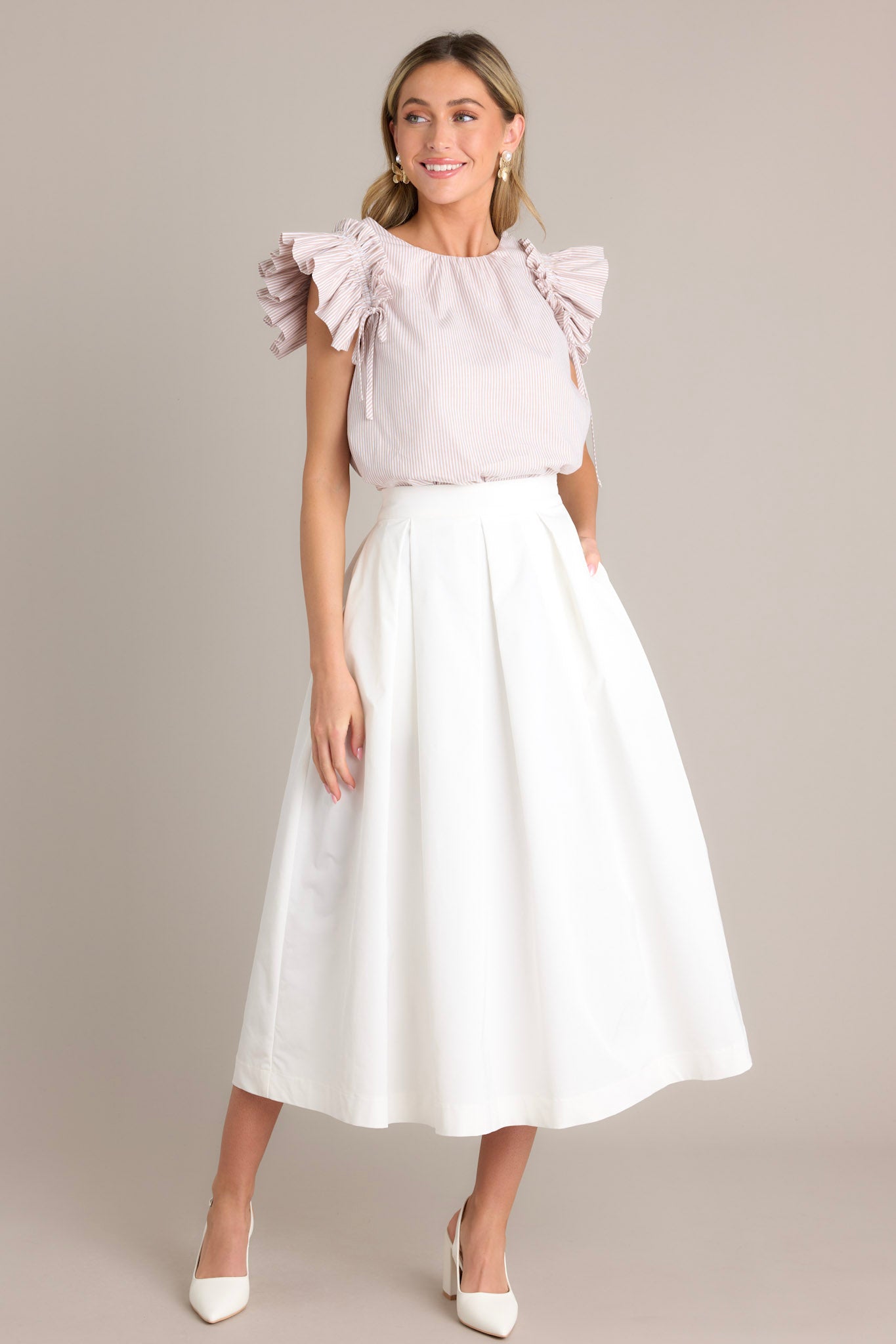 Angled full body view of this white midi skirt that features a high waisted design, a discrete side zipper, and a thick waistline.