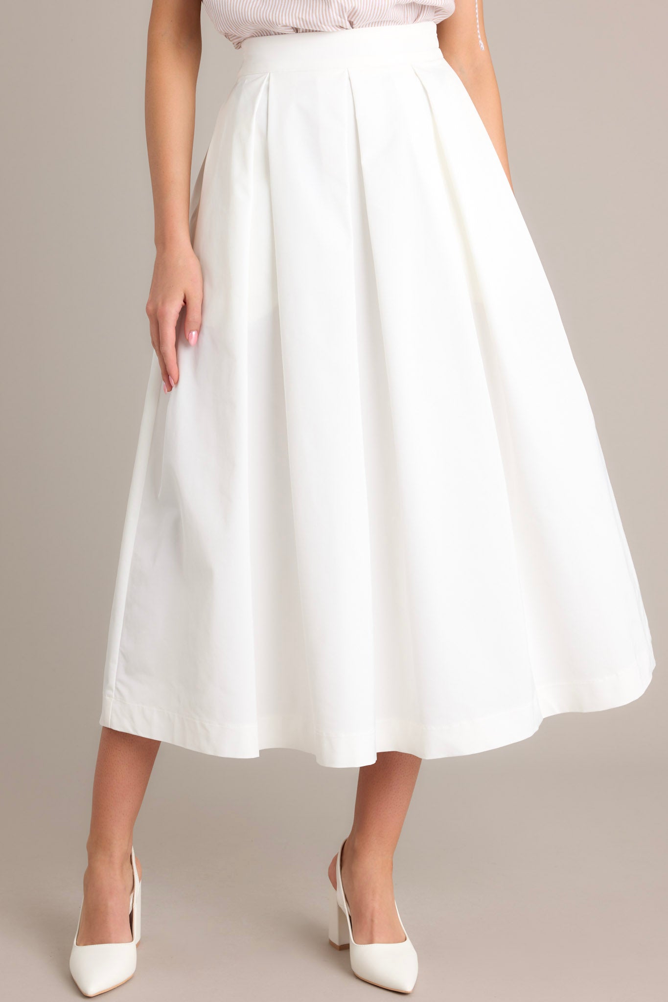 This white midi skirt features a high waisted design, a discrete side zipper, and a thick waistline.