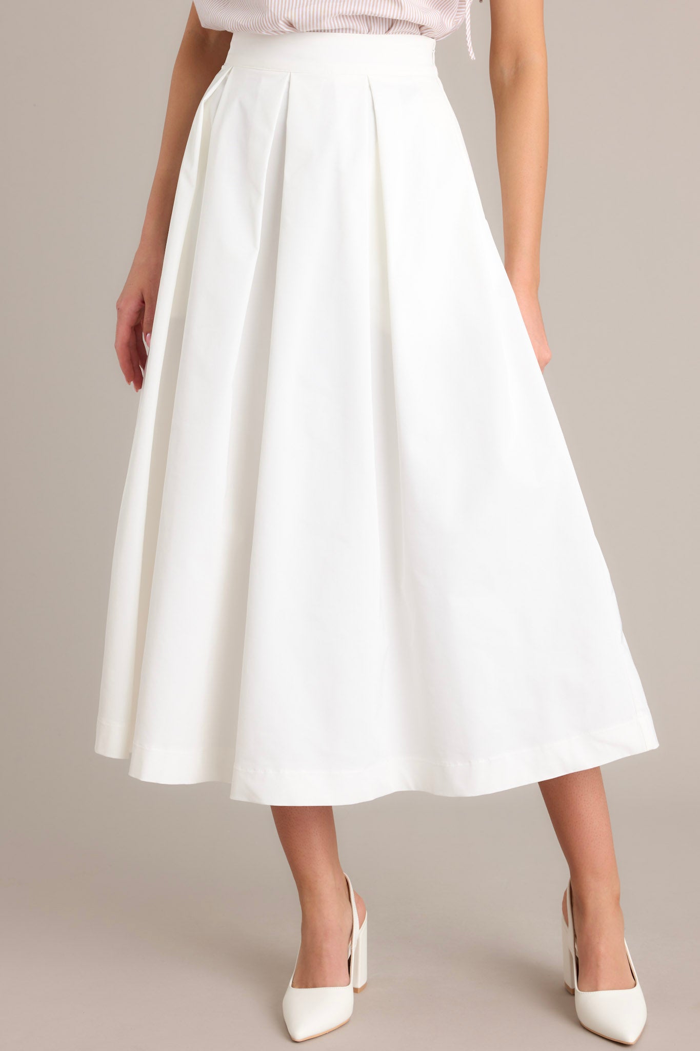 Front view of this white midi skirt that features a high waisted design, a discrete side zipper, and a thick waistline.