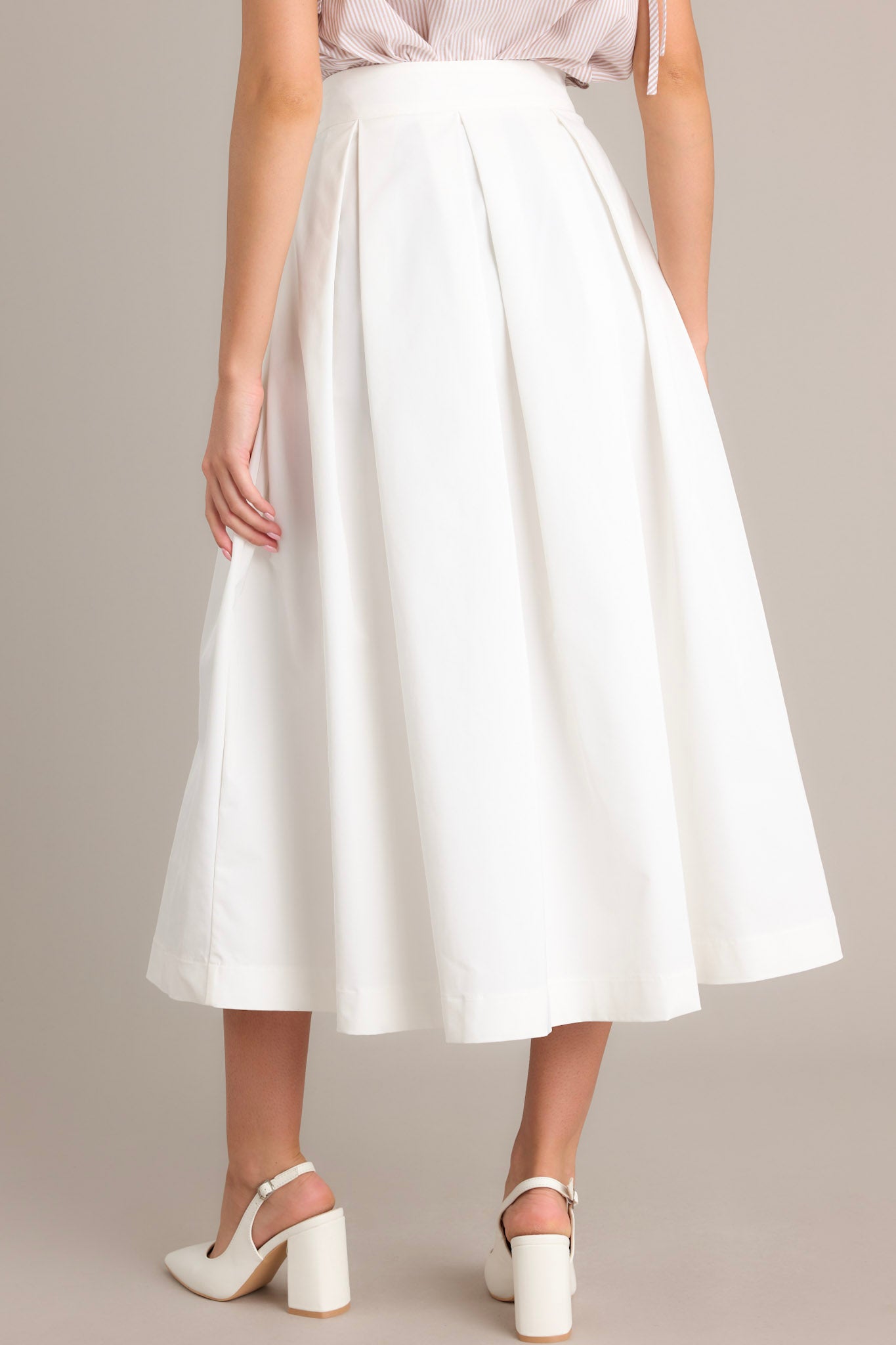 Back view of this white midi skirt that features a high waisted design, a discrete side zipper, and a thick waistline.