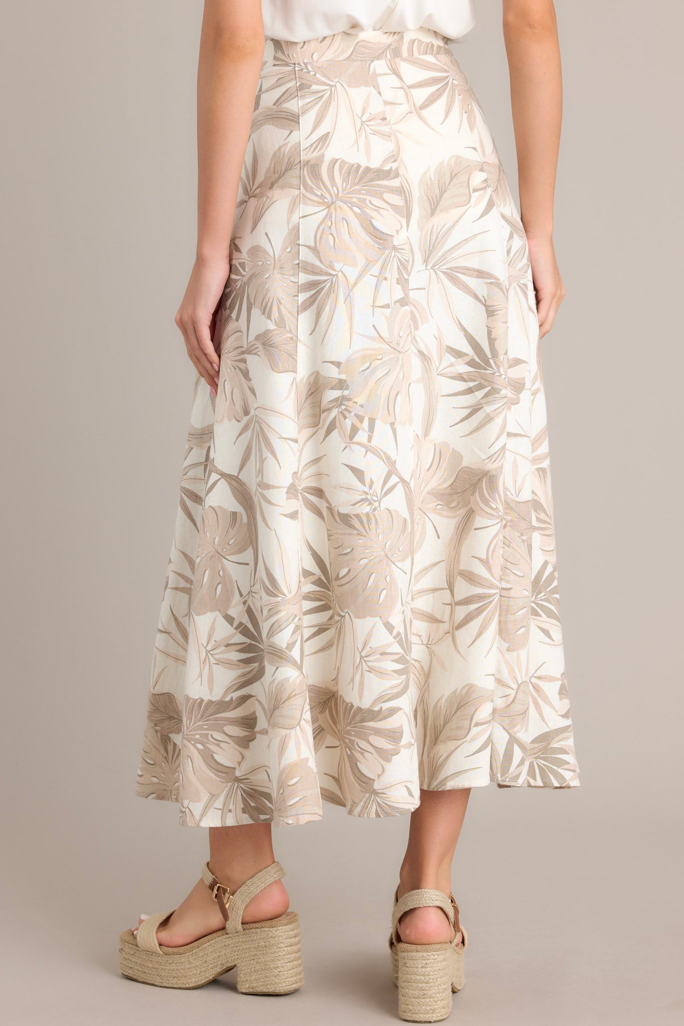 Back view of a sandstone maxi skirt highlighting the high waisted design and flowing silhouette.