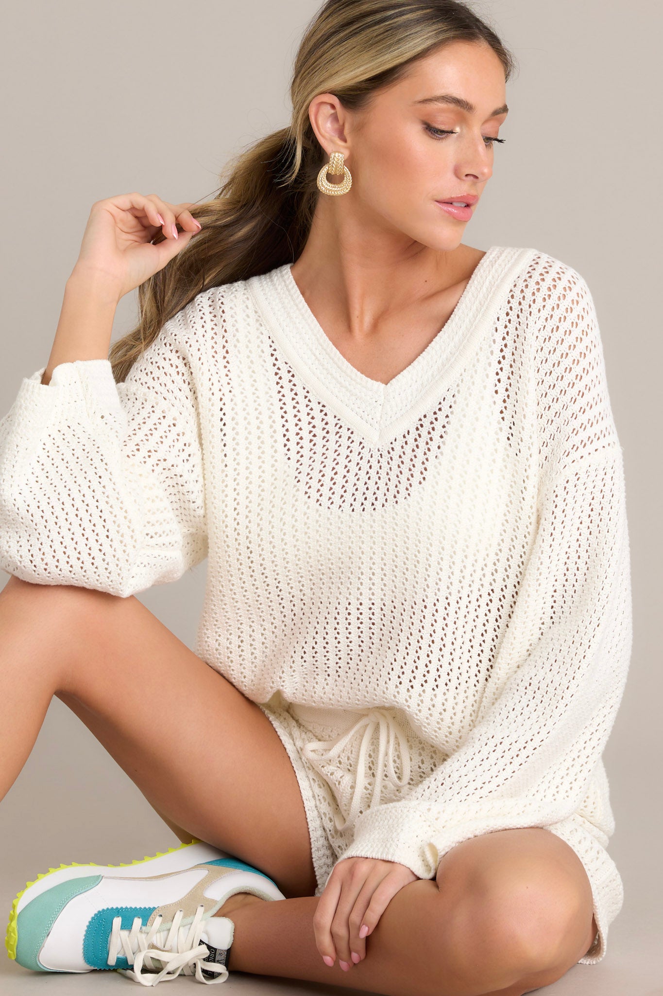 This ivory sweater features a v-neckline, a relaxed fit, an open knit design, and wide long sleeves.