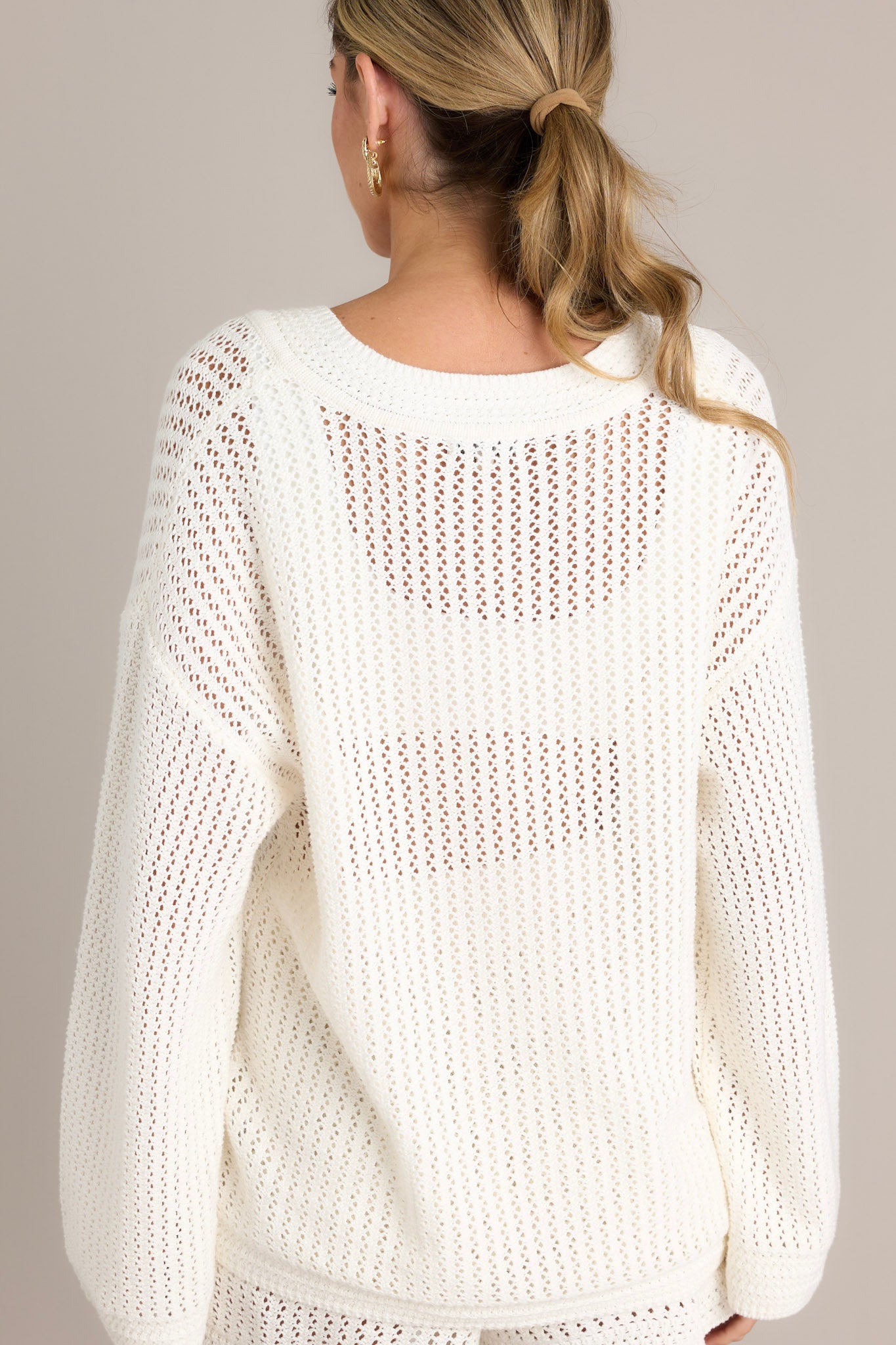 Back view of an ivory sweater featuring an open knit design and a relaxed fit.