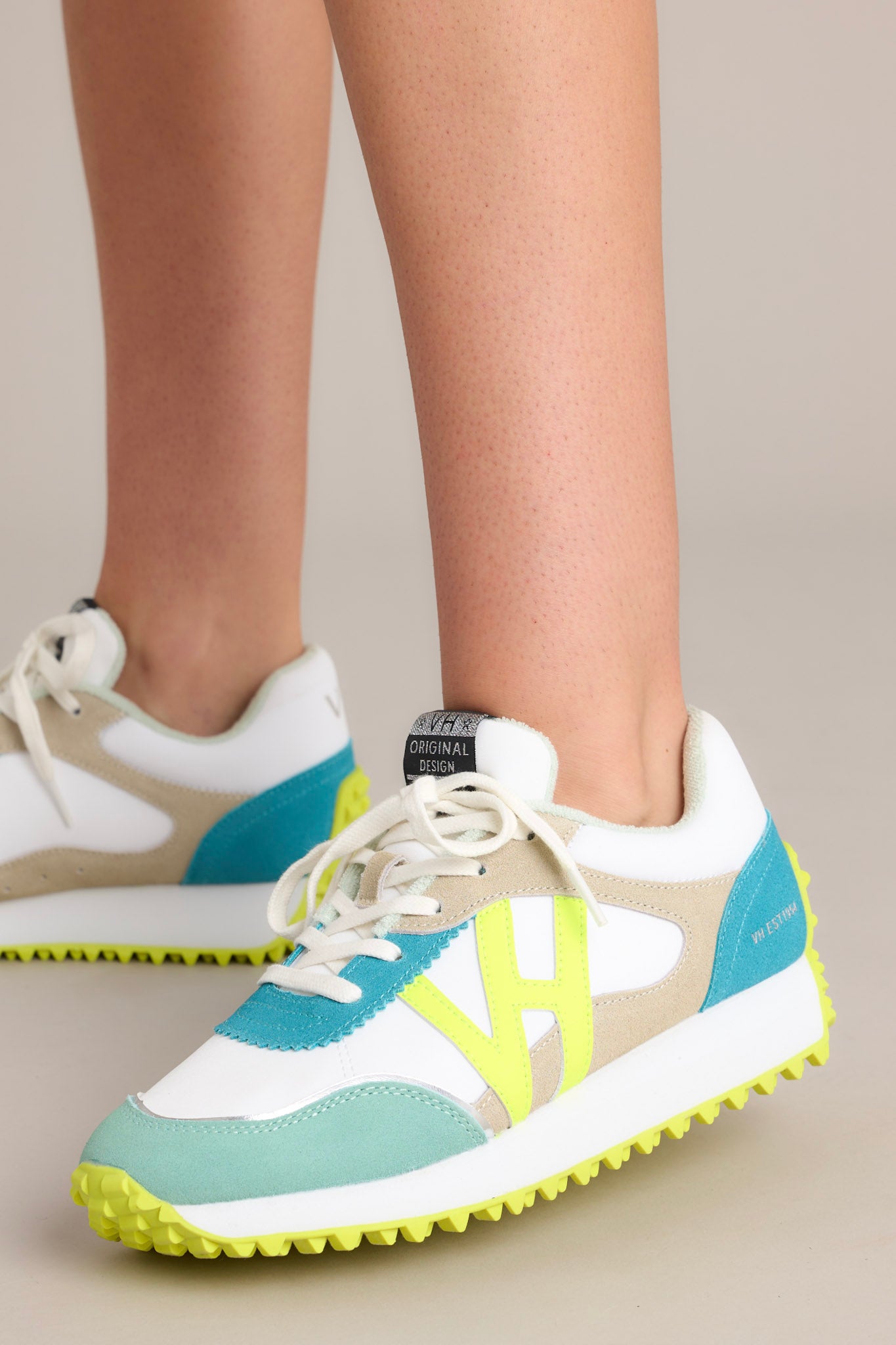 Movement shot of these neon yellow sneakers that feature a rounded toe, functional laces, subtle pops of color, a slight platform, and a heavily textured sole.