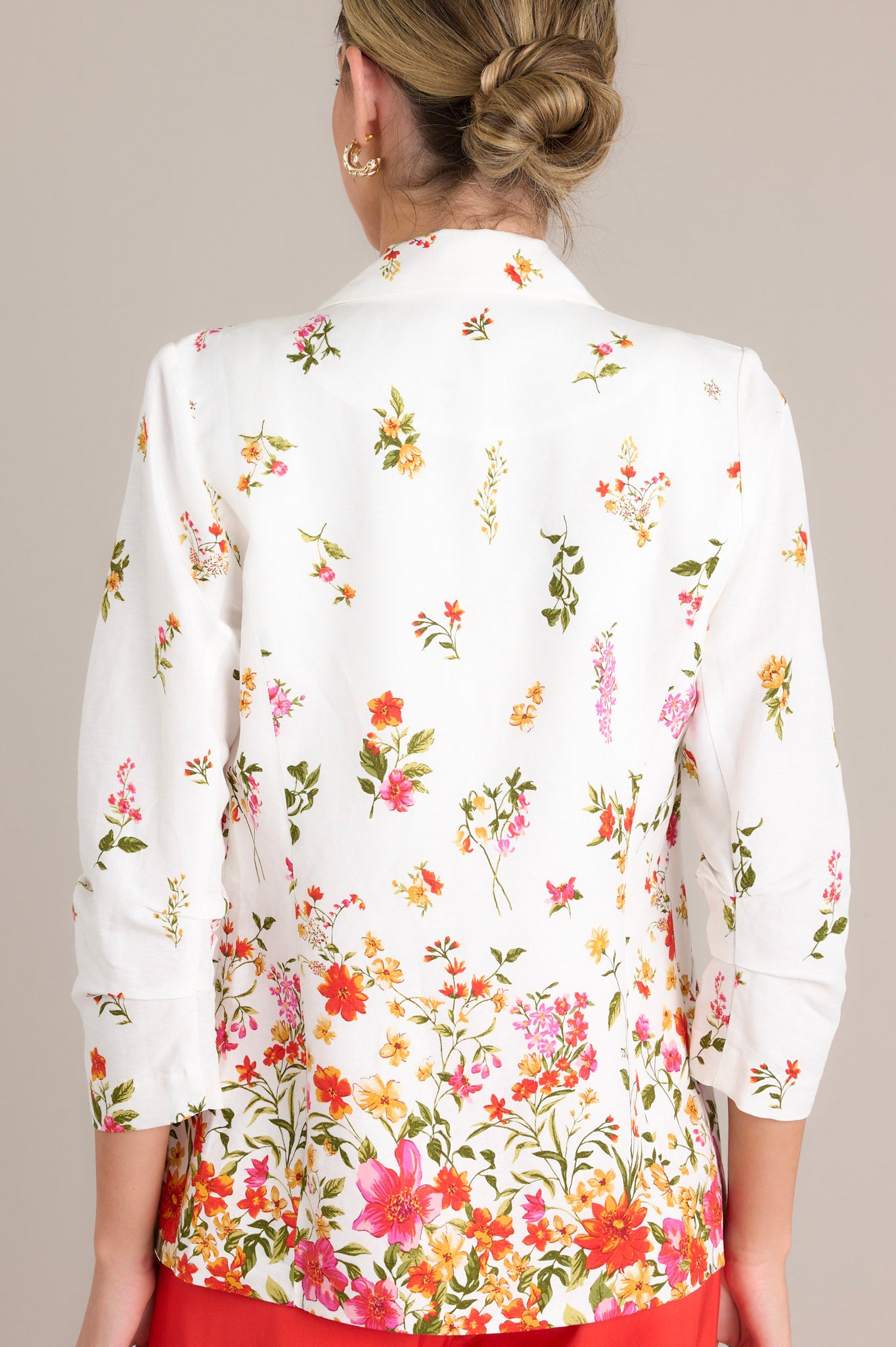 Back view of a blazer highlighting the floral pattern and the ruched detail on the 3/4 sleeves.