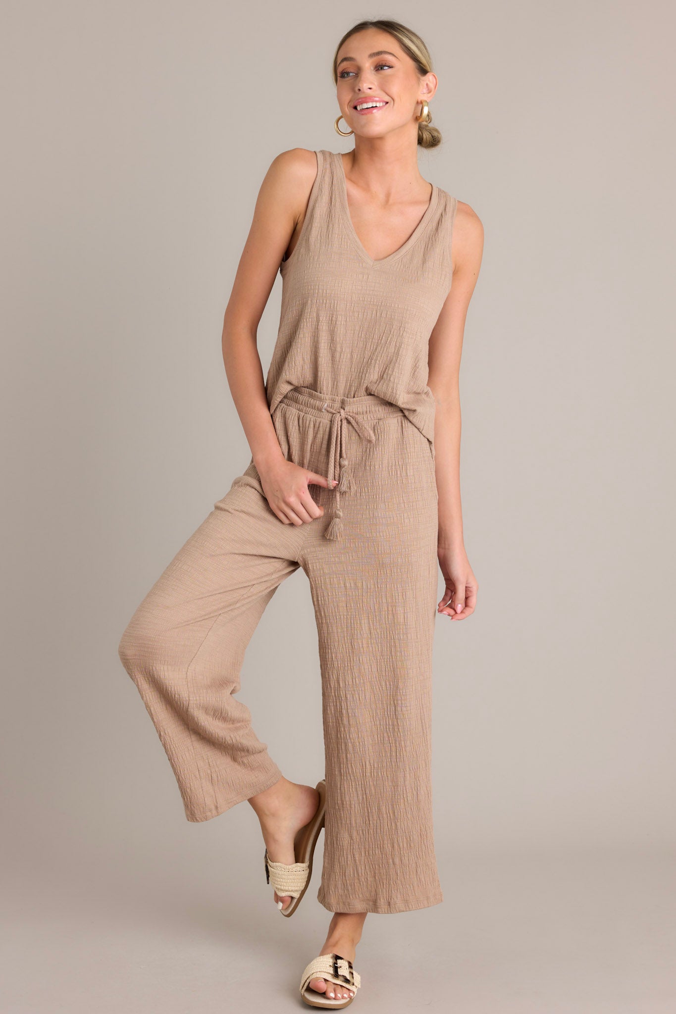 Full length view of a tan tank top featuring a V-neckline, sleeveless design, textured material, and relaxed fit.
