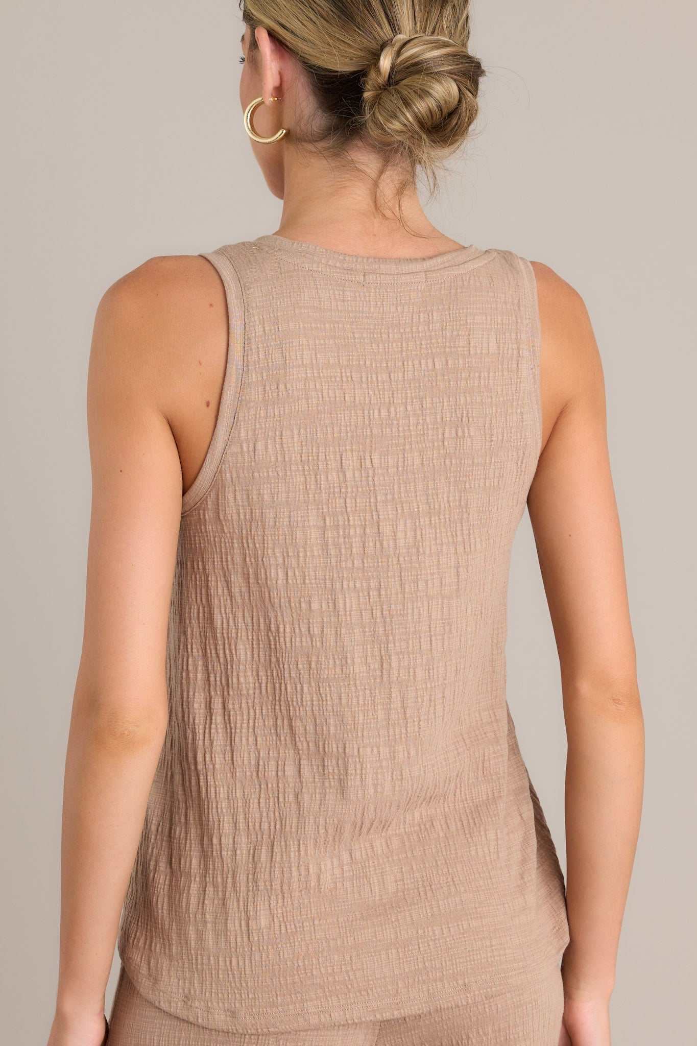 Back view of a tan tank top showcasing the sleeveless design and textured material.