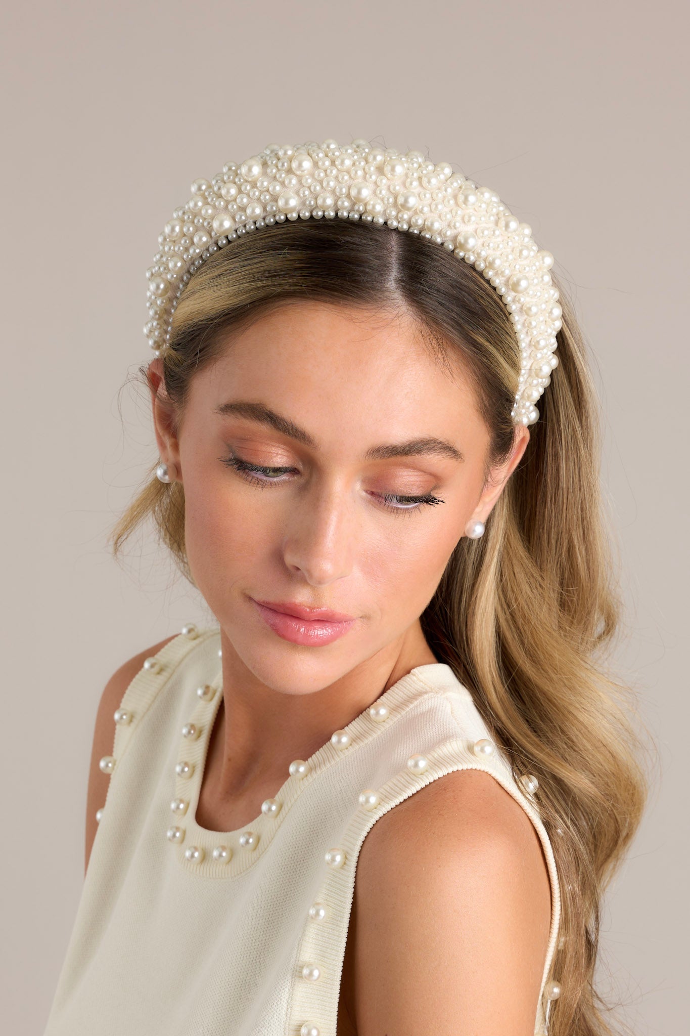 This headband is adorned with many white faux pearls varying in size, and a thick band.