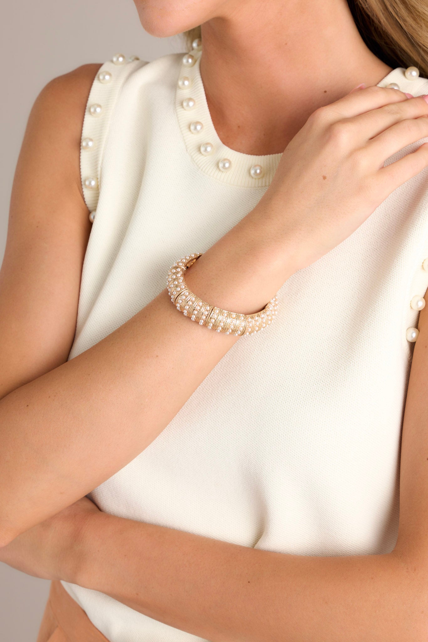 This gold bracelet is adorned with multiple small ivory faux pearls, and elastic bands underneath to accommodate stretch.
