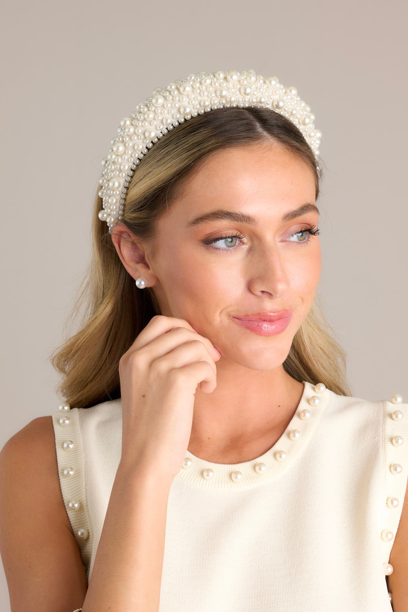 Front angled view of this headband that is adorned with many white faux pearls varying in size, and a thick band.
