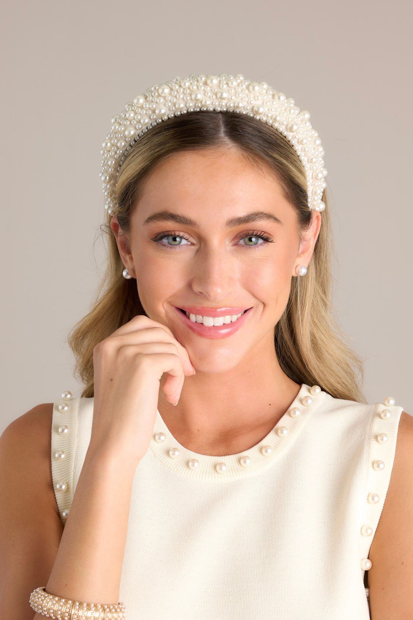 Front view of this headband that is adorned with many white faux pearls varying in size, and a thick band.