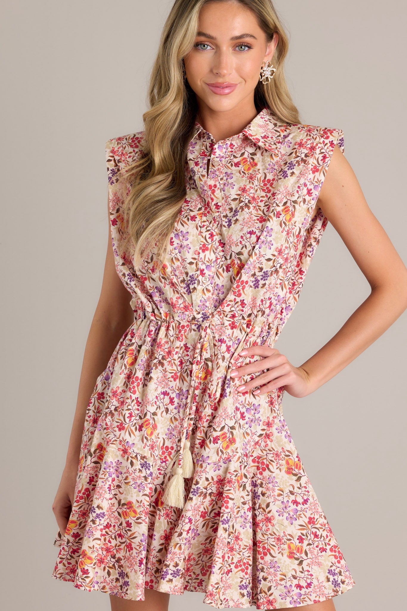 Focused view on the buttons down the bust of this beige floral multi mini dress, along with the collared neckline and padded shoulders.