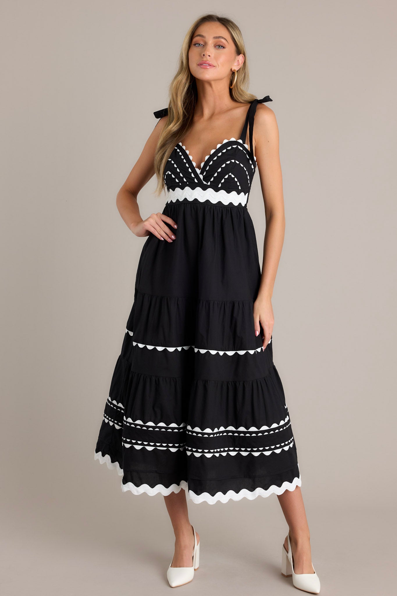 This black maxi dress features a v-neckline, thick self-tie straps, ricrac bust detailing, a fully smocked back, a ricrac waistband, tiers with ricrac detailing, and a ricrac hemline.