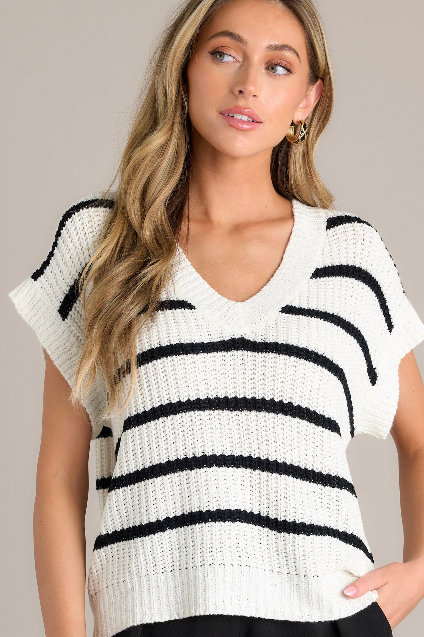 Front angled view of a stripe sweater top featuring a ribbed v-neckline, soft chunky knit material, horizontal stripes, a ribbed hemline, and ribbed short sleeves