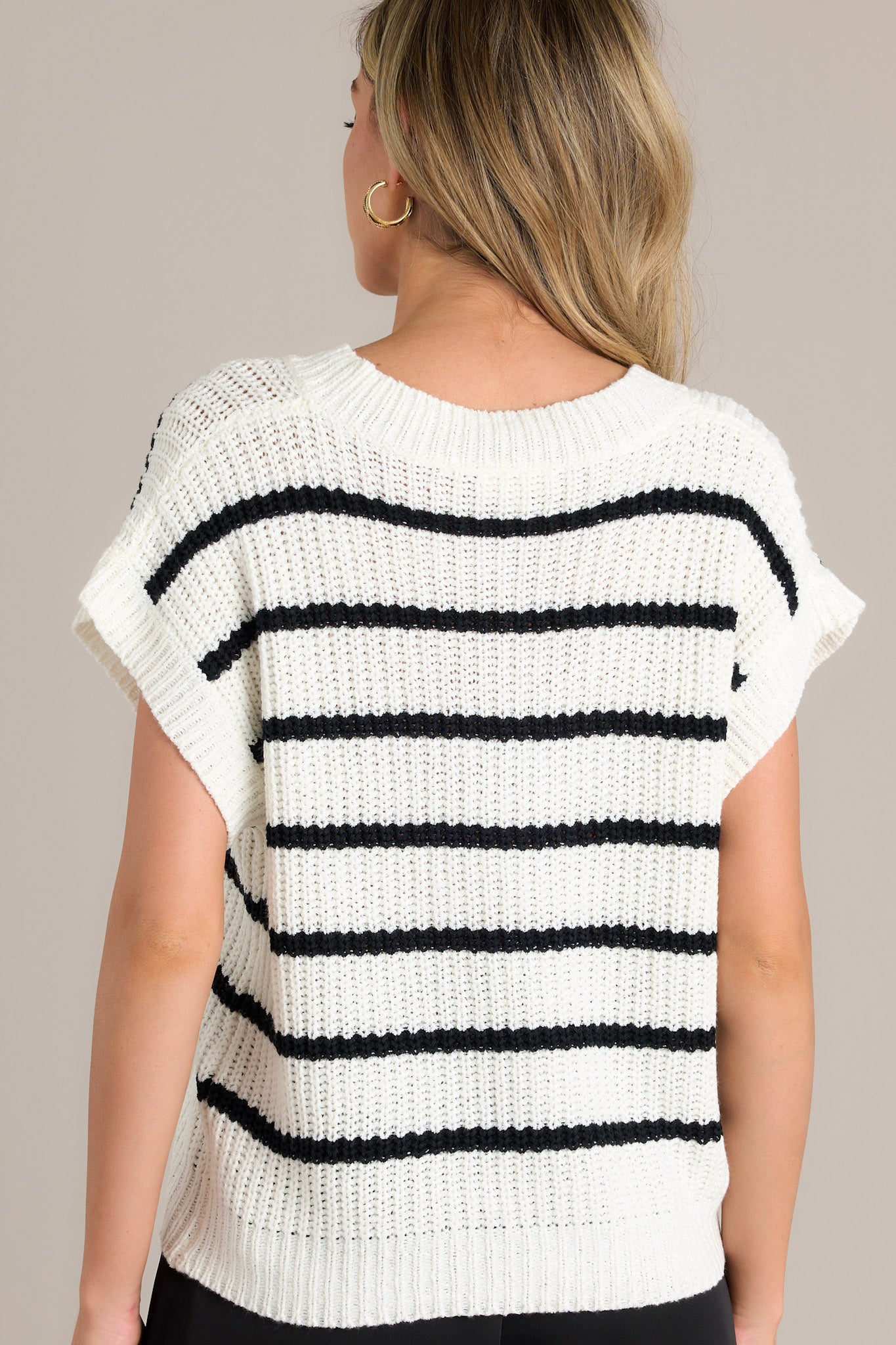 Back view of a stripe sweater top highlighting the horizontal stripes, soft chunky knit material, and the ribbed hemline.