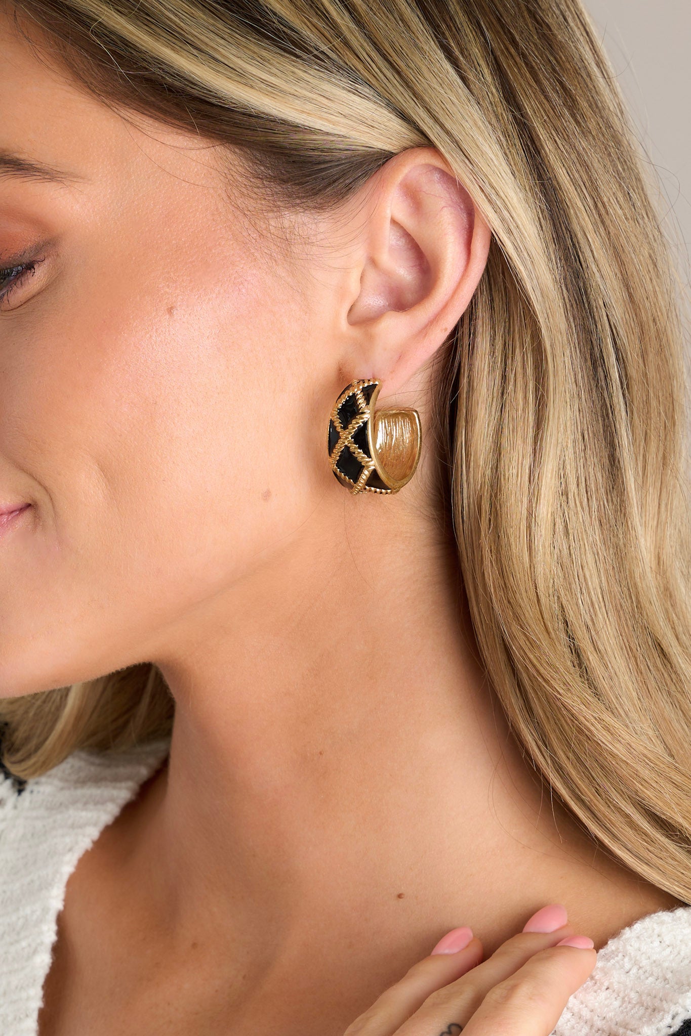 These black earrings feature an incomplete hoop design, a gold textured design, and secure post backings.