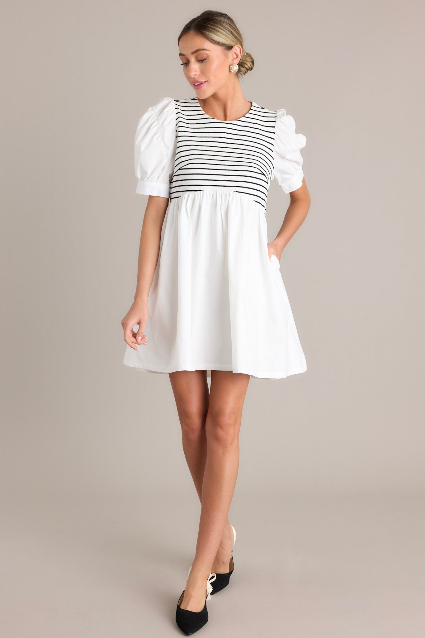 This stripe mini dress features a round neckline, a keyhole with a functional button, a striped bodice, functional hip pockets, and short cuffed puff sleeves.