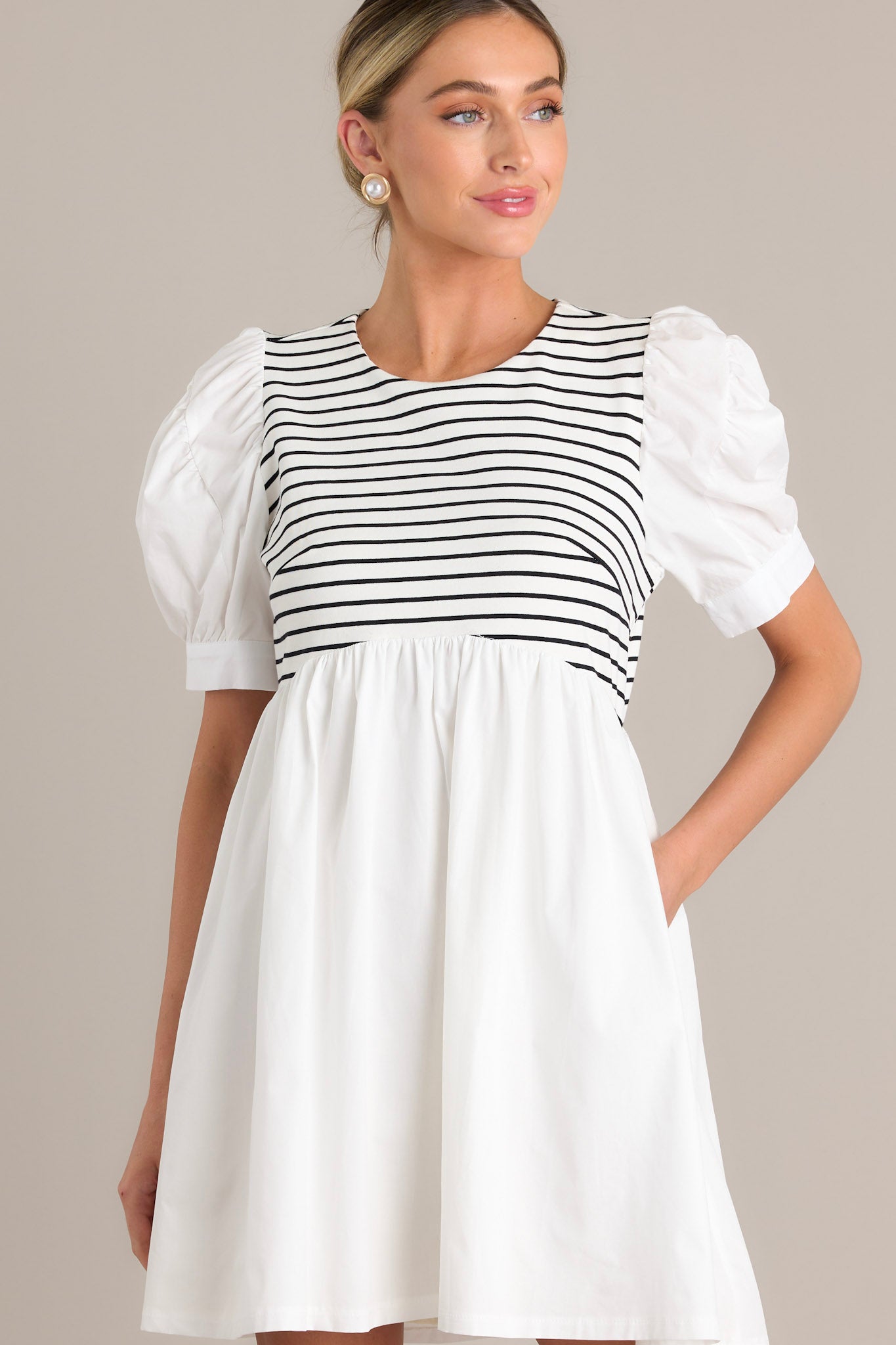 Front view of this white mini dress featuring functional pockets, and puff sleeves. 