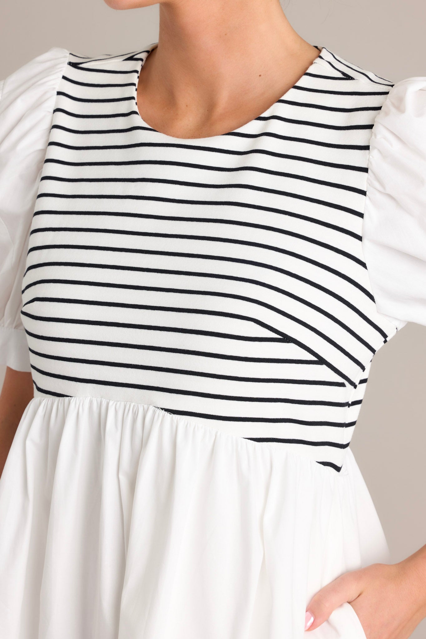 Close up view of the black and white stripe bodice of this white mini dress. 