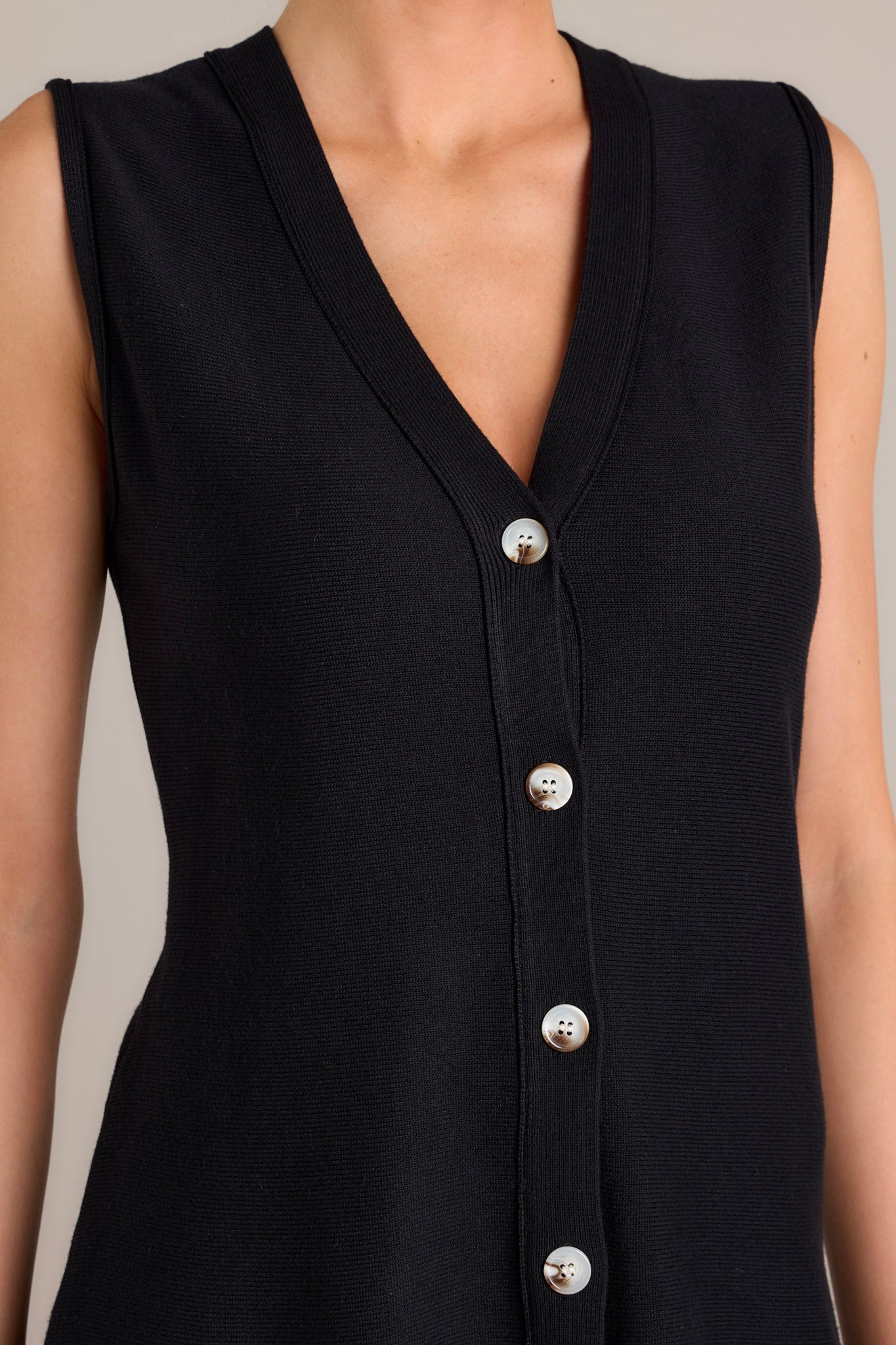 Close up view of this black sleeveless top showcasing the lightweight knit fabric. 