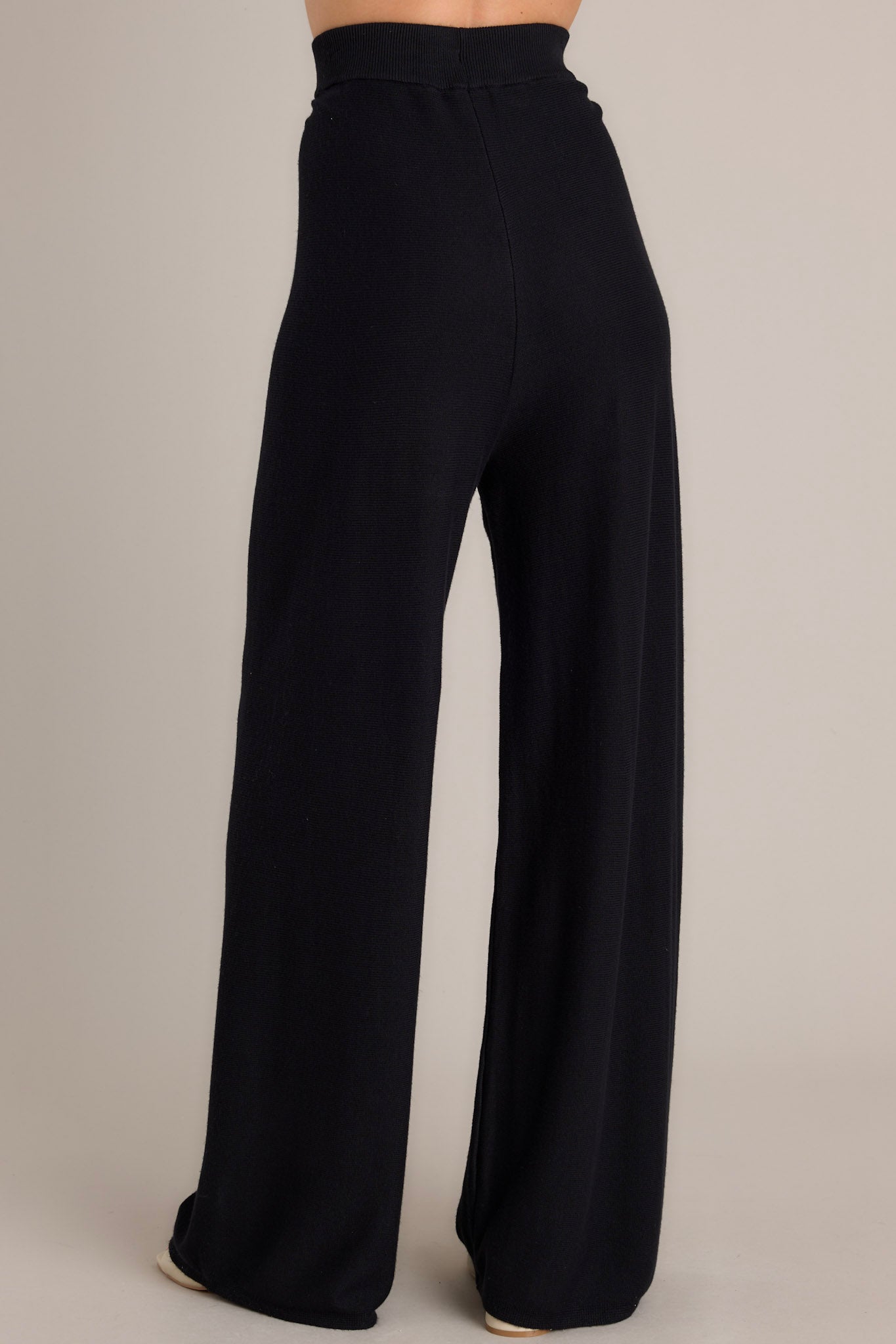 Back view of these black pants feature a high waisted design, a thick elastic waistband, a super soft material, and a wide leg.