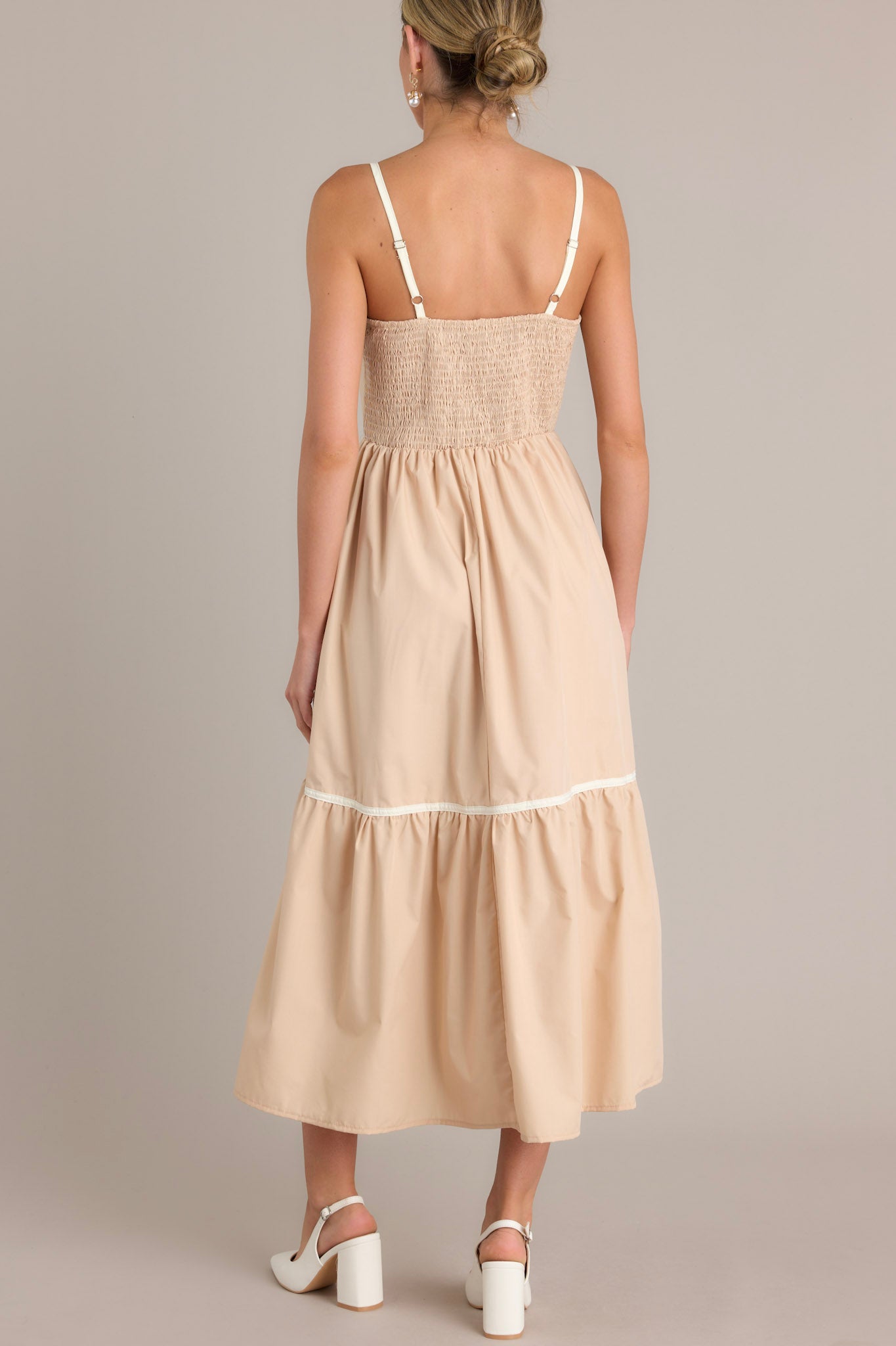Back view of a beige maxi dress highlighting the fully smocked back, thin adjustable straps, and overall fit.