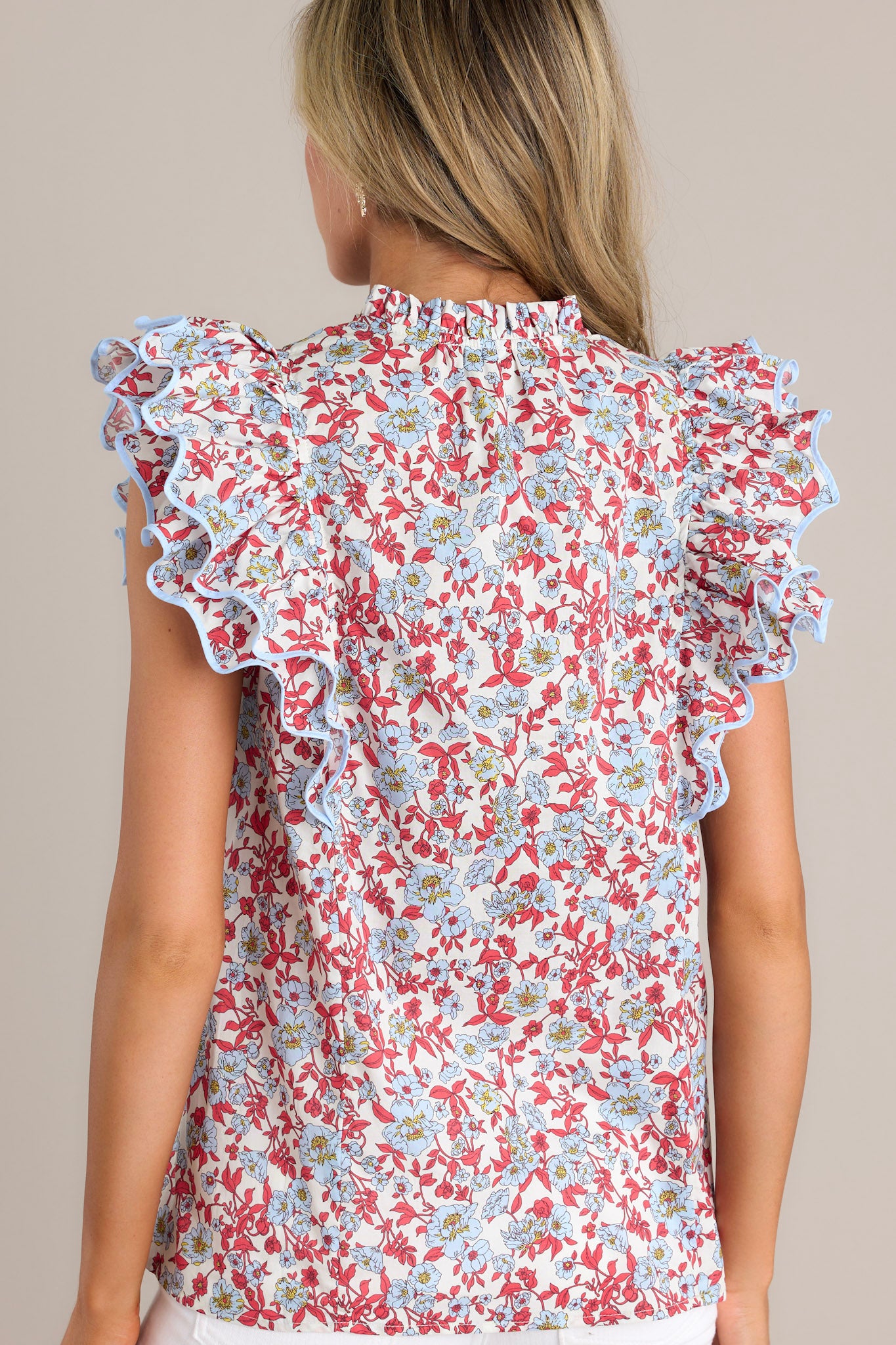 Back view of a red top highlighting the floral print and ruffled short sleeves with ricrac detailing.