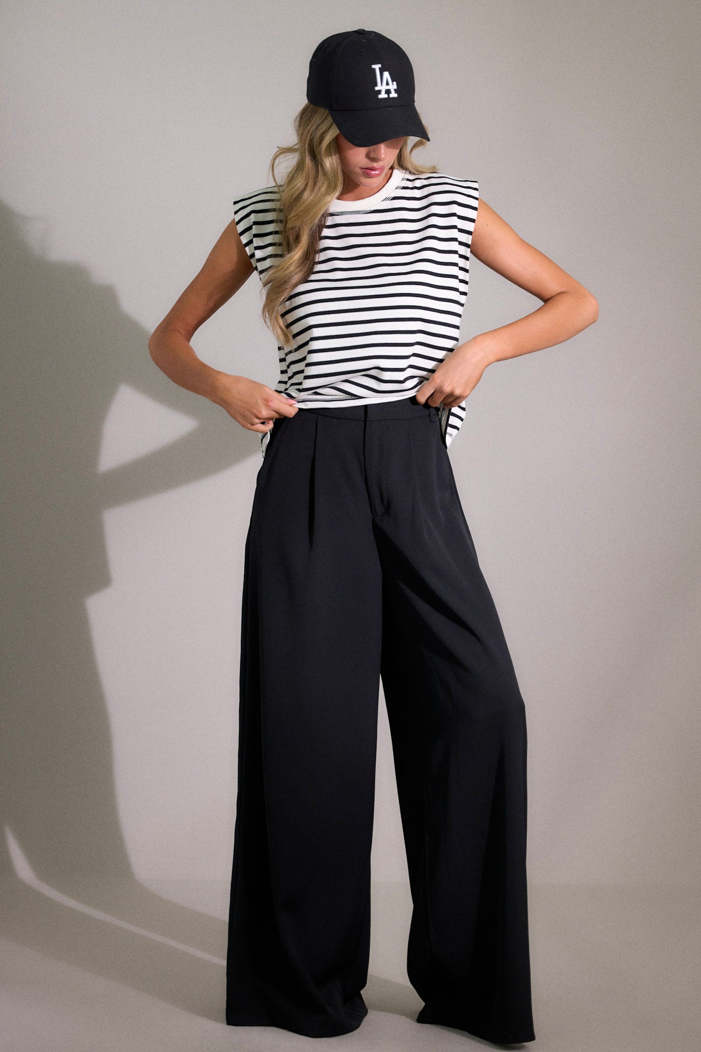 Full length view of black pants featuring a high waist fit, a hook and bar closure, belt loops, pockets, and a wide leg