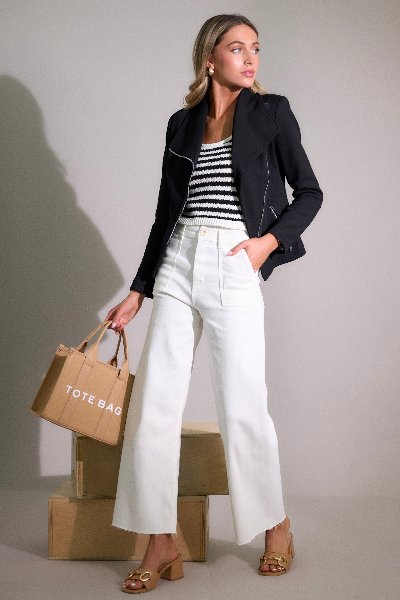 Action shot of white jeans with a high waisted design, a classic button & zipper closure, belt loops, functional front & back pockets, a wide leg design, and a raw hemline, highlighting the fit and flow of the jeans.