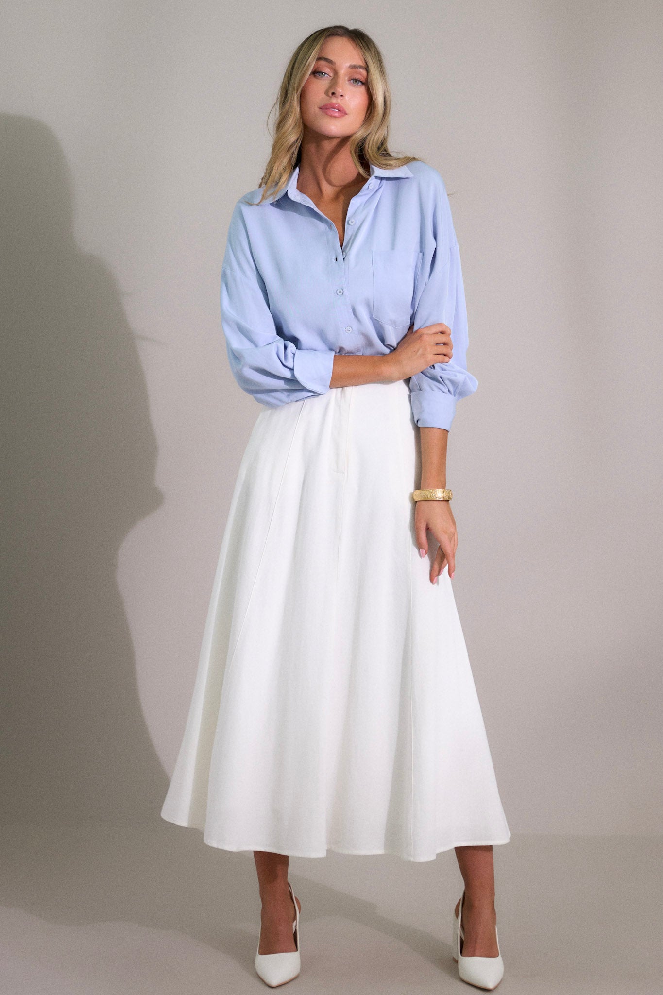 Full body this ivory midi skirt that features a high waisted design, a button & zipper closure, functional hip pockets, visible front & back seams, and a flowing silhouette.