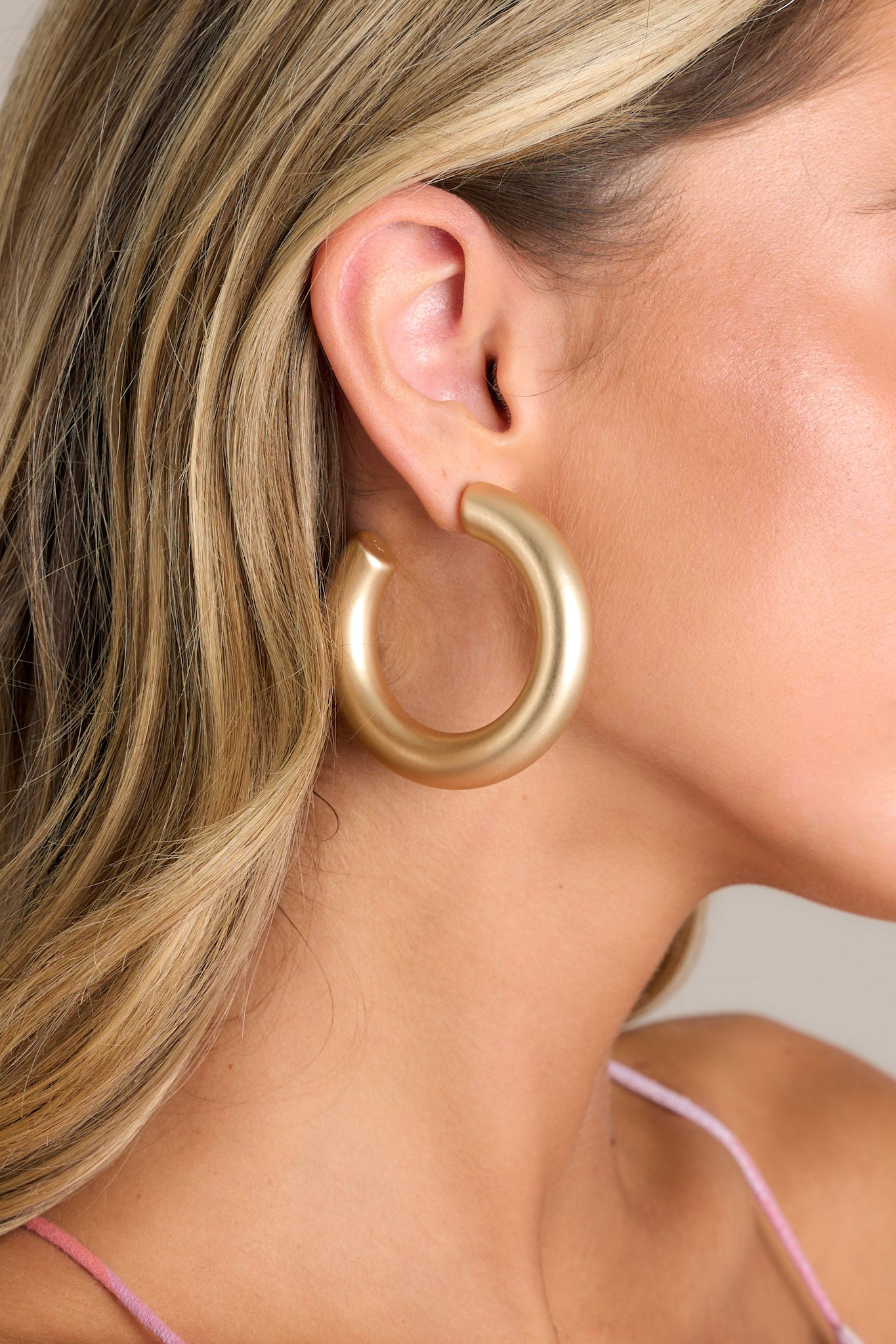 Close-up of these gold hoop earrings featuring a matte gold finish, thick design, and a secure post backing.