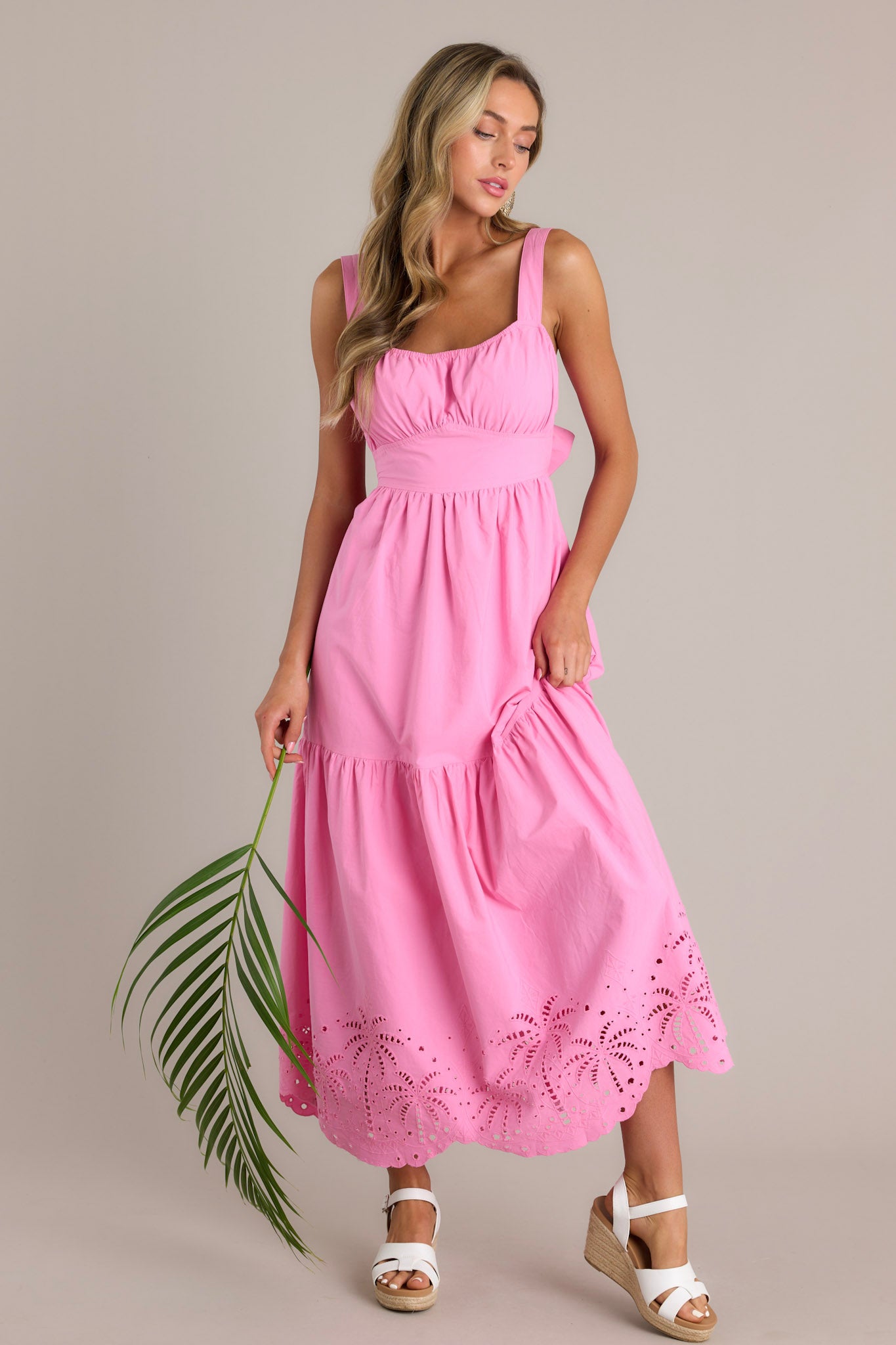 This pink midi dress features an elastic square neckline, thick adjustable straps, a thick waistband with a self-tie back feature, an open lower back, a single tier, palm eyelet detailing, and a scalloped hemline.