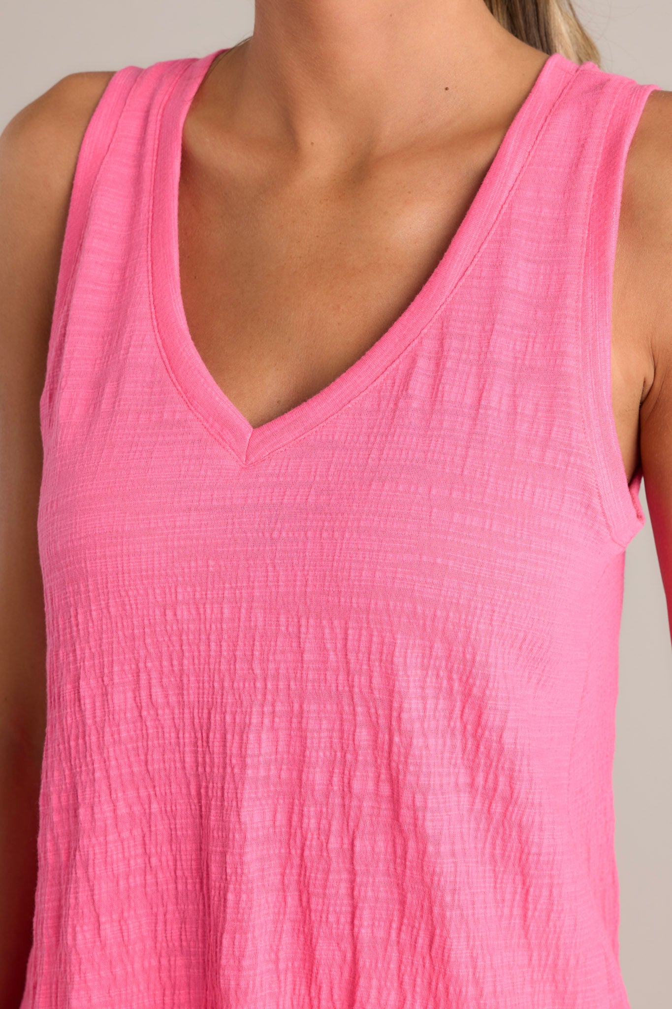 A detailed close-up of the pink tank top's fabric, focusing on the textured material and stitching near the neckline.