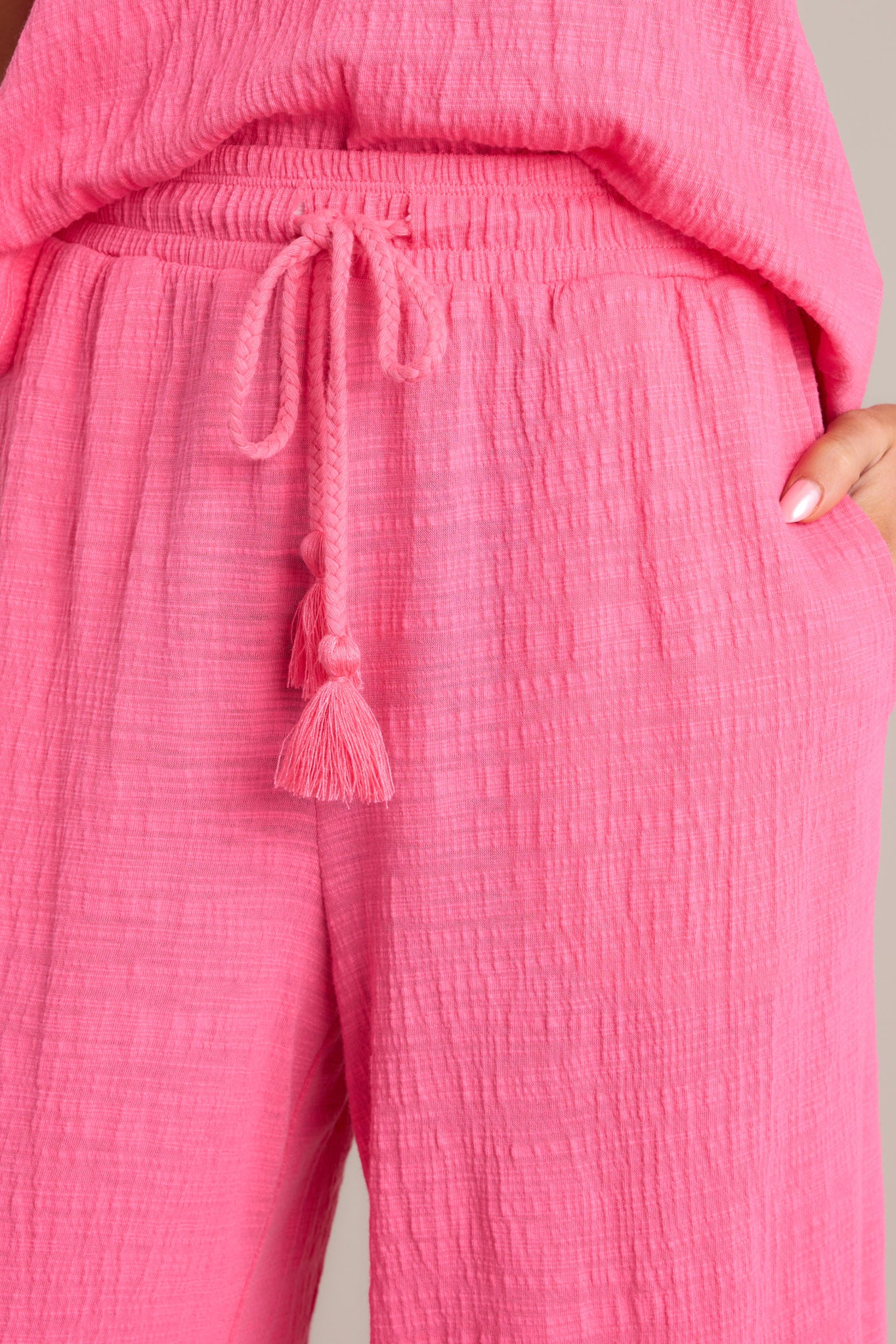 Detailed close-up of the pink pants' textured material and self-tie drawstring.