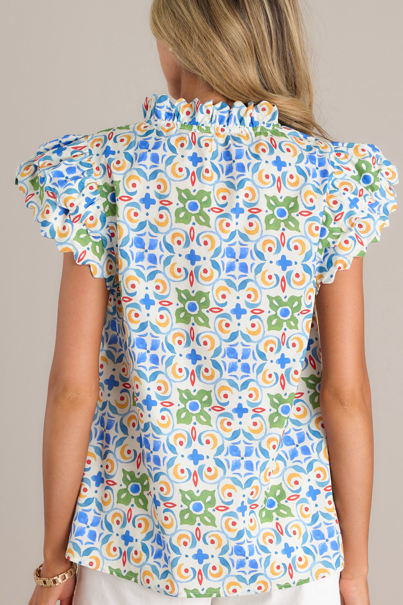 Back view of a white multi top highlighting the unique multi-colored print and the ruffled short sleeves.