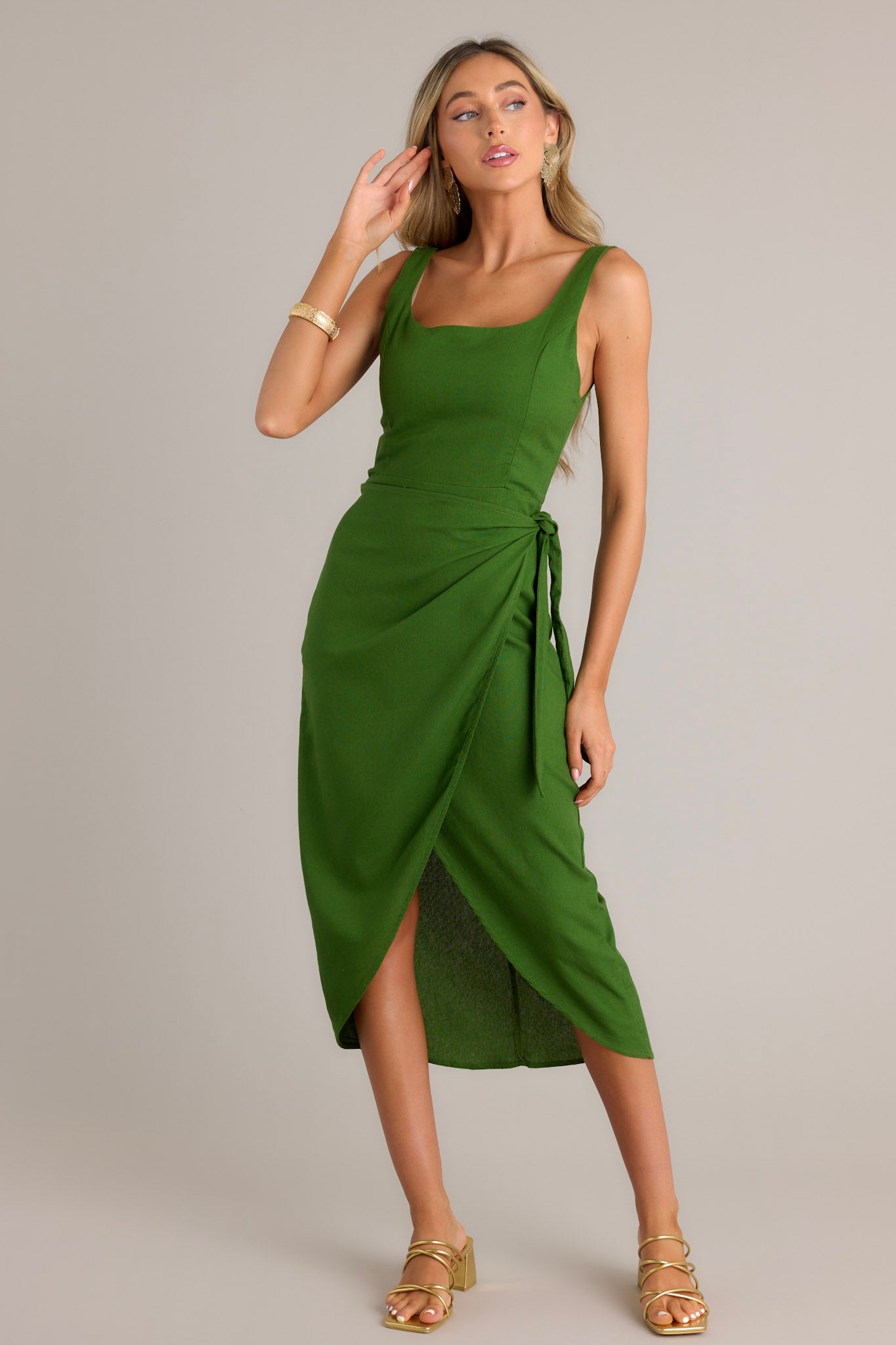 Front view of a green midi dress featuring a square neckline, thick straps, a self-tie wrap feature, and a front slit.