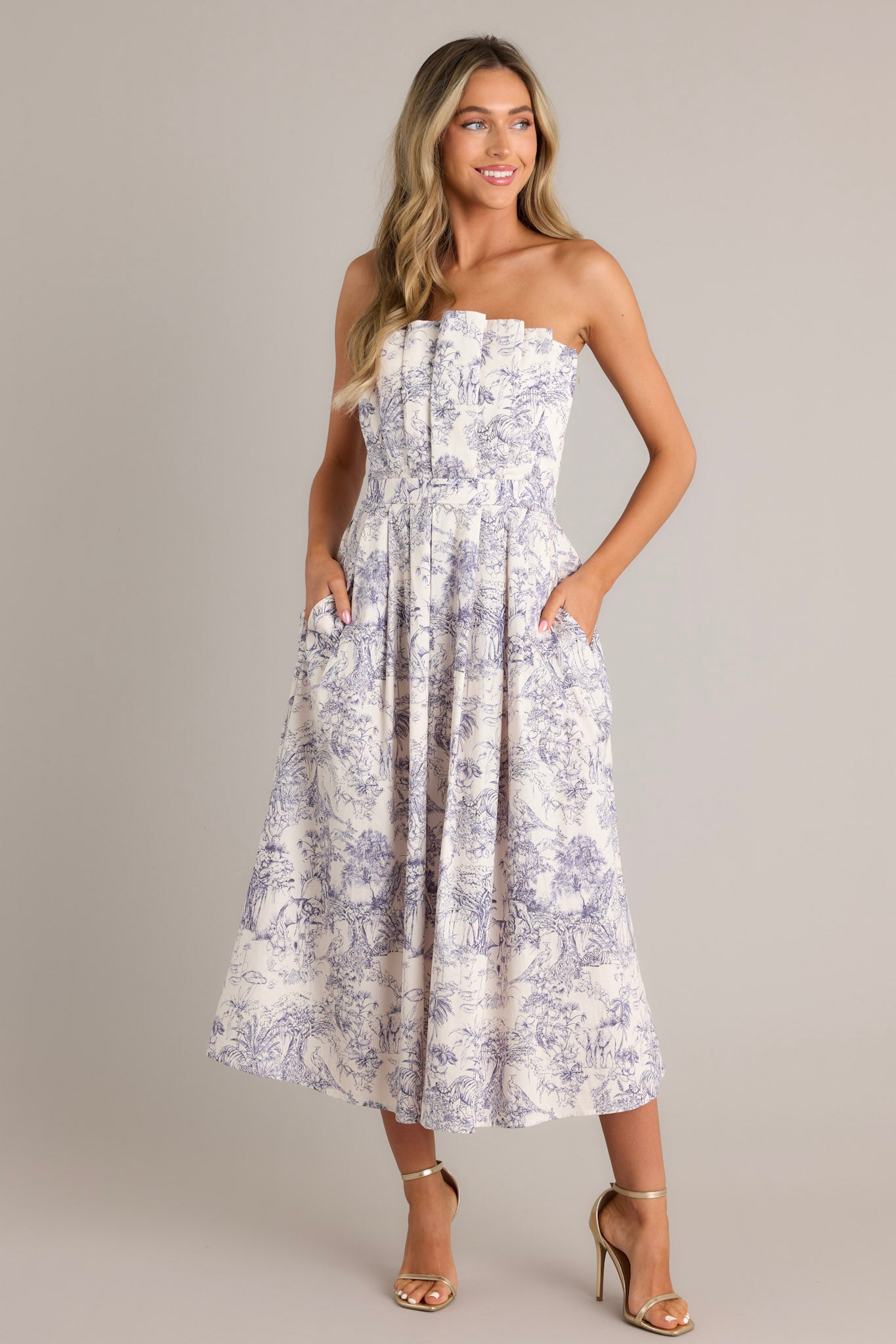 Blue toile strapless midi dress with a structured, pleated bodice, functional pockets, and a smocked back.