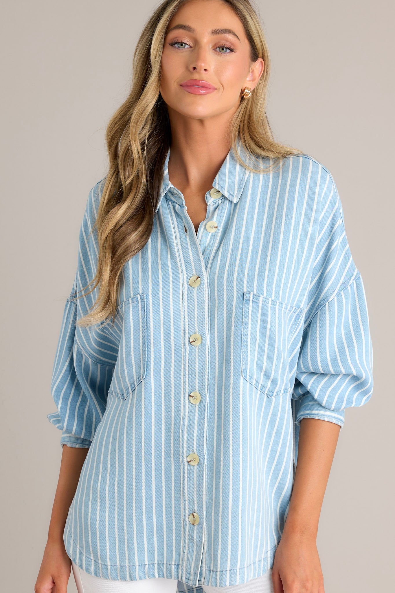 Front view of a top featuring a collared neckline, functional buttons down the front, two functional bust pockets, long sleeves with buttoned cuffs, a scoop bottom hem, and a super soft material.