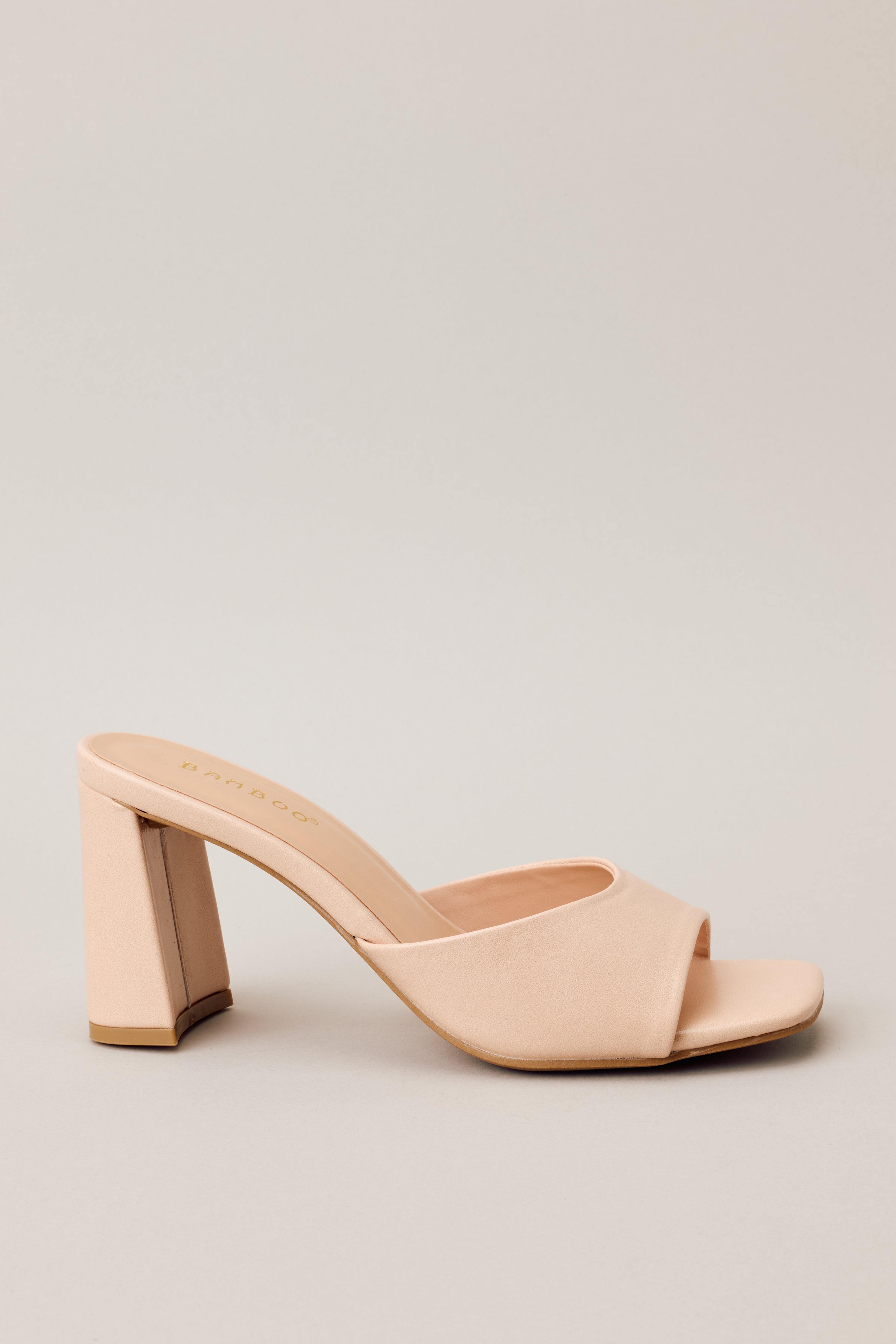 Side view of these beige heels that feature a square toe, a slip-on design, a strap over the top of the foot, and a thick block heel.