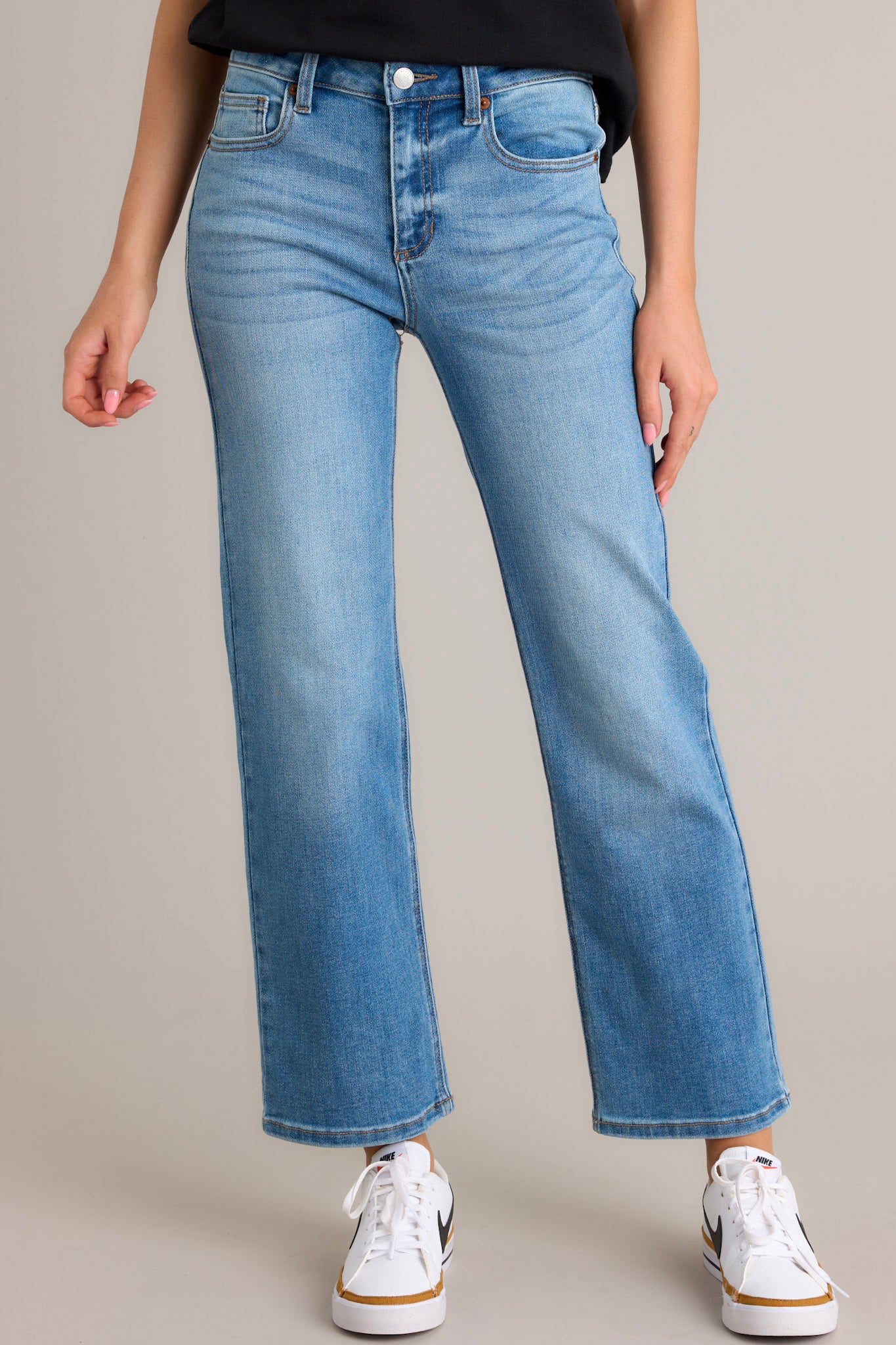 These medium wash jeans feature a high waist design, a zipper and button closure, functional belt loops and pockets, and a straight leg.