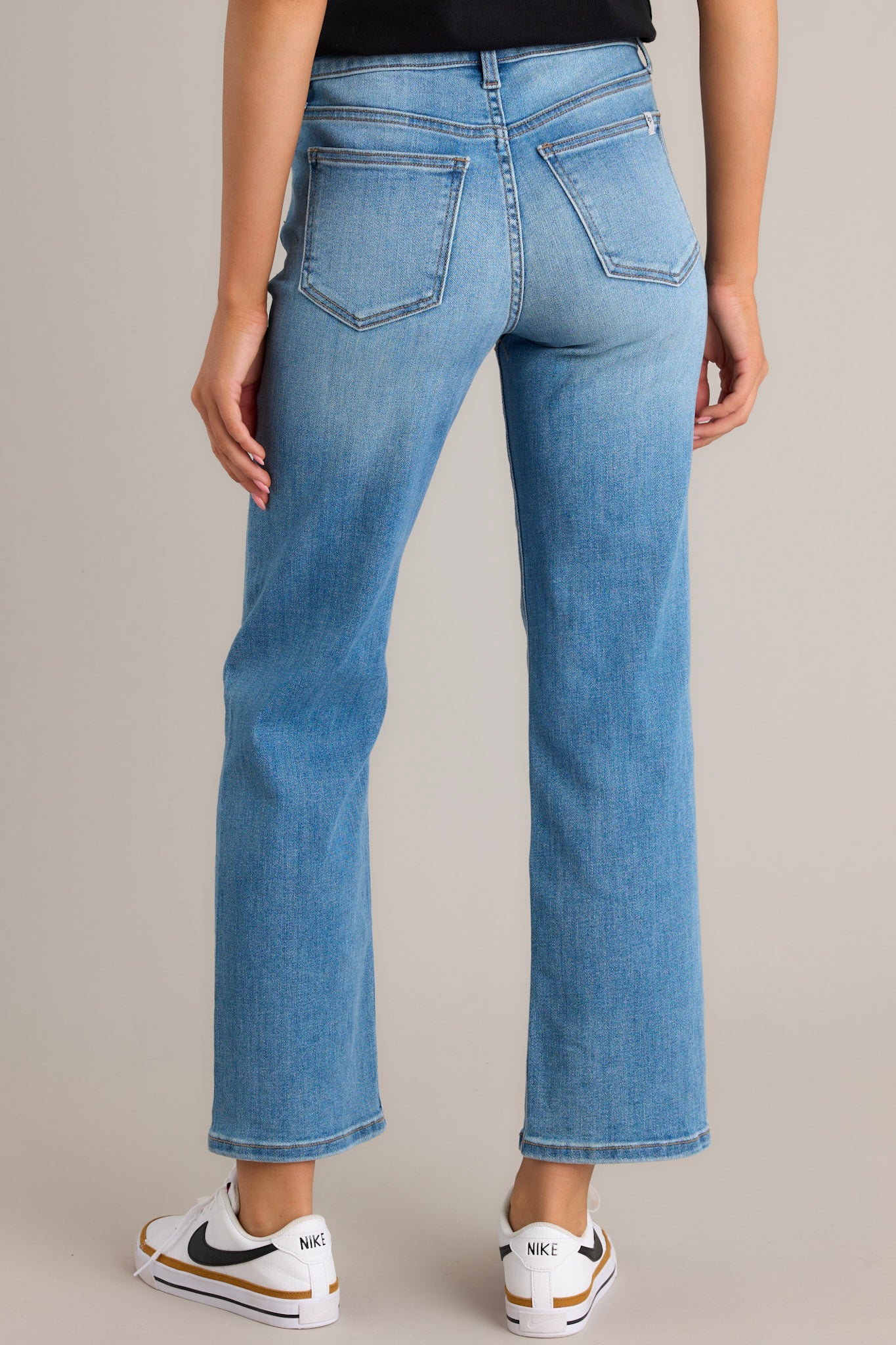 Back view of these jeans that feature a high waist design, a zipper and button closure, functional belt loops and pockets, and a straight leg.