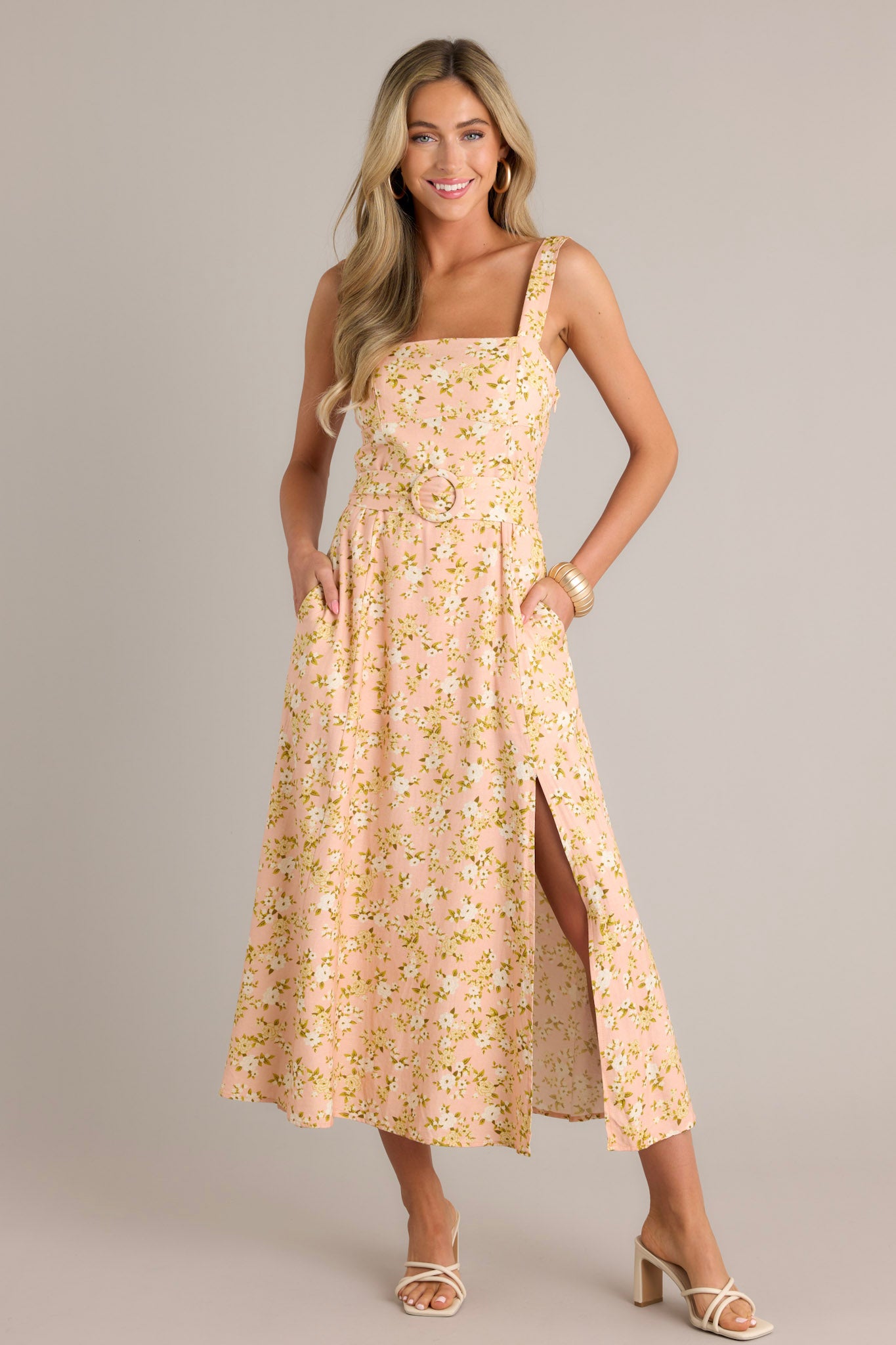 Front view of a peach maxi dress featuring a square neckline, thick adjustable straps, a functional pull-through waist belt, belt loops, functional hip pockets, and a front slit.