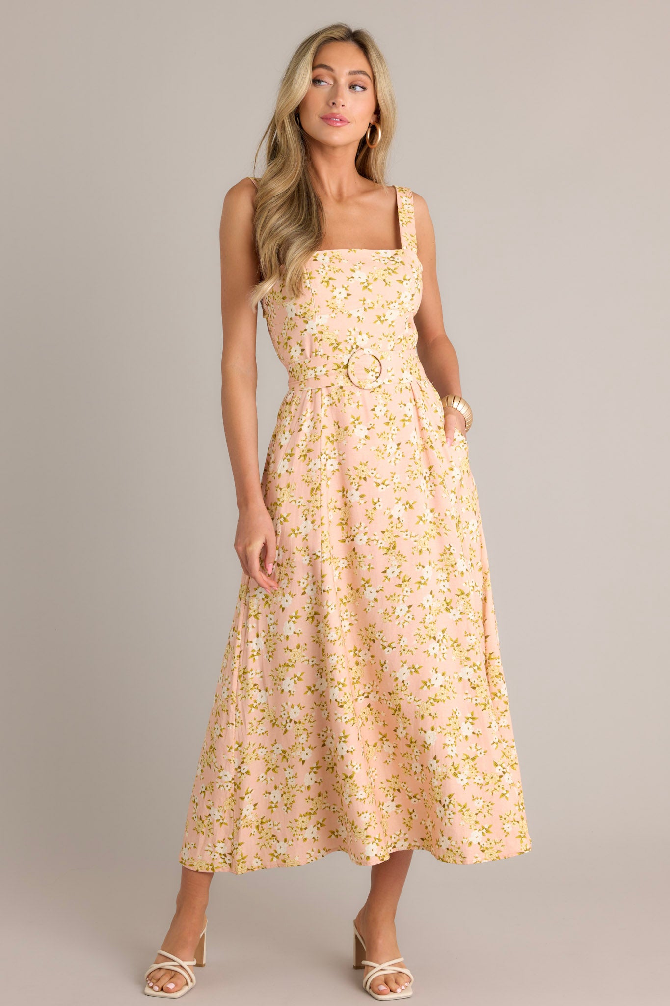 Full length view of a peach maxi dress with a square neckline, thick adjustable straps, a smocked back insert, a discrete zipper, a functional pull-through waist belt, belt loops, functional hip pockets, and a front slit