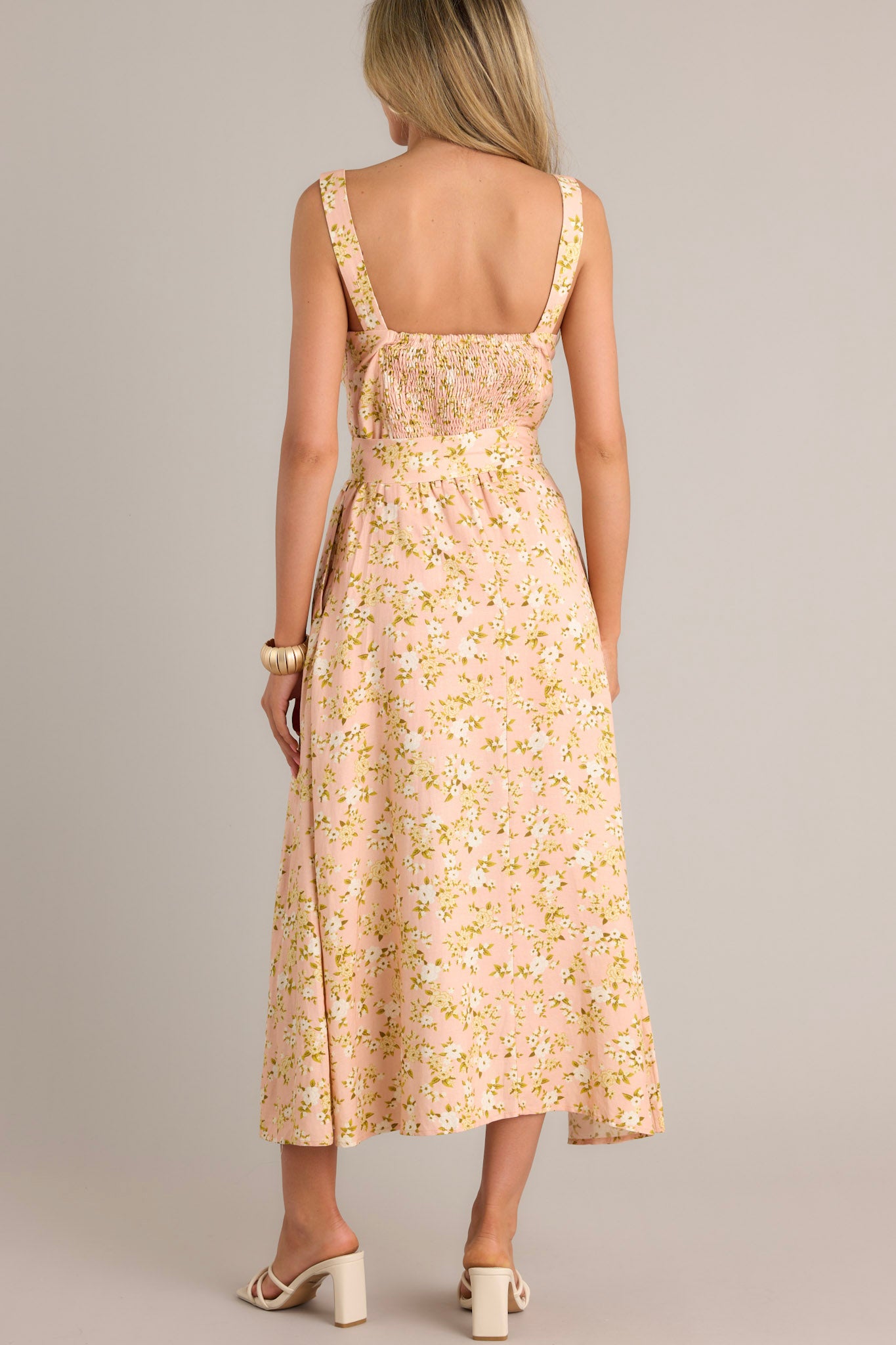 Back view of a peach maxi dress highlighting the smocked back insert, discrete zipper, and overall fit.