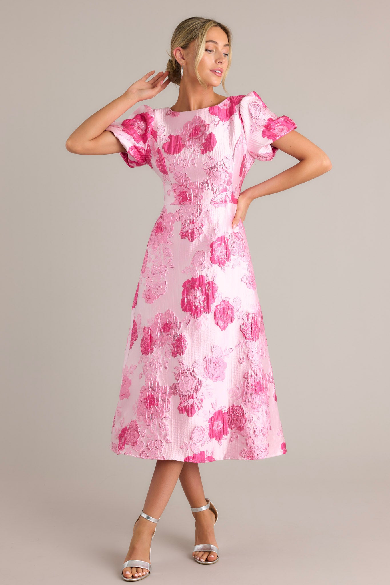 Front view of a pink dress featuring a boat neckline, short puff sleeves, and a midi length.