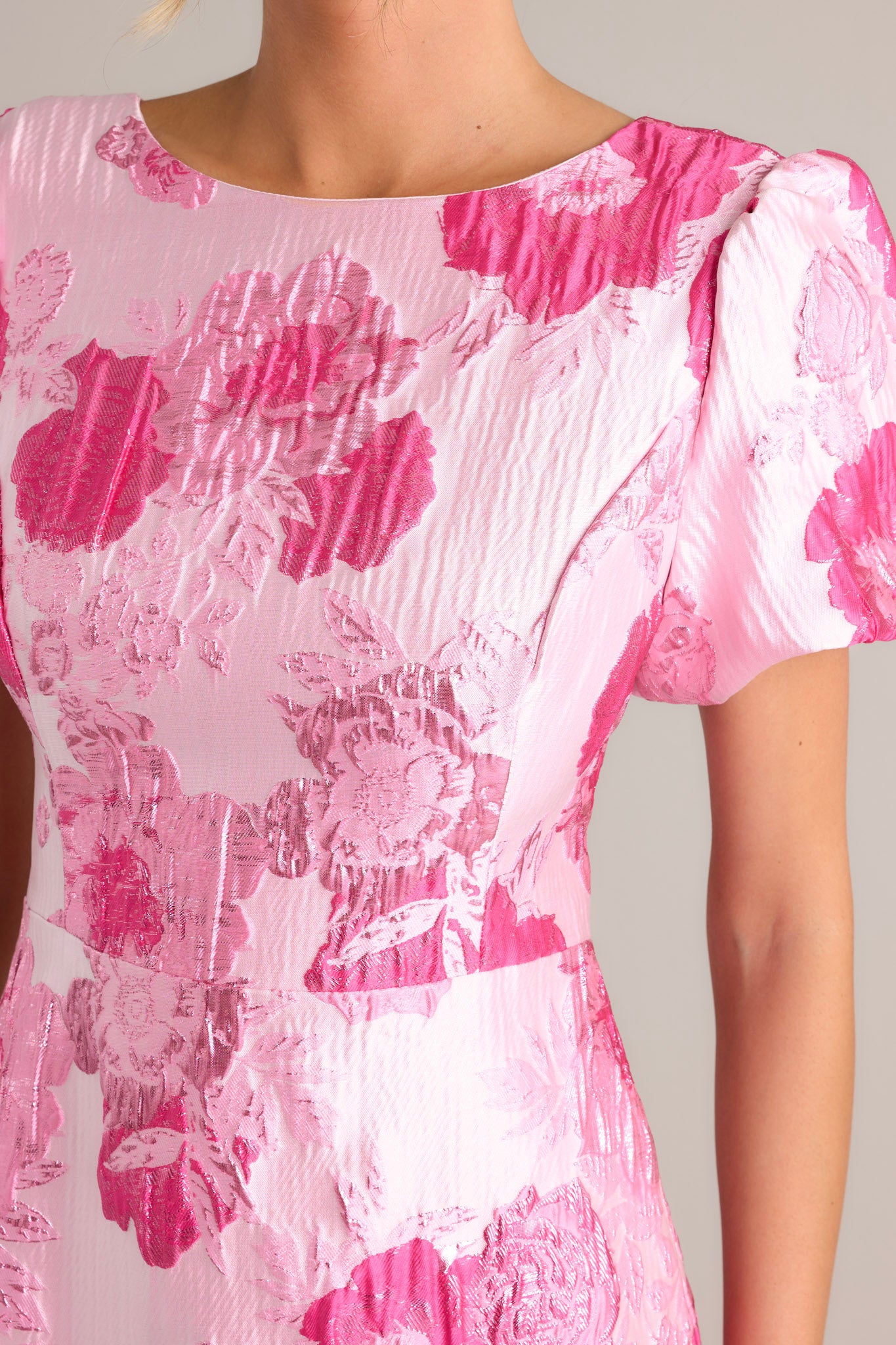 Close-up of the pink dress showing the boat neckline, short puff sleeves, and deep v-back with a zipper closure.