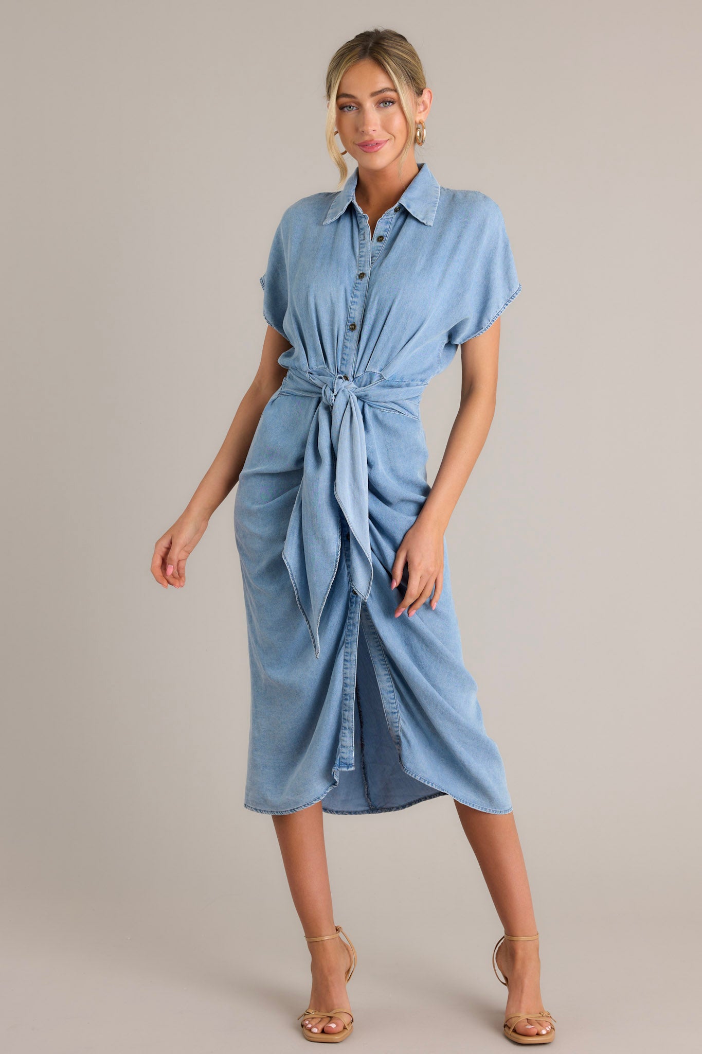 Full front view of this dress that features a collared neckline, a full button front, a self-tie waist feature, a front slit, and short sleeves.